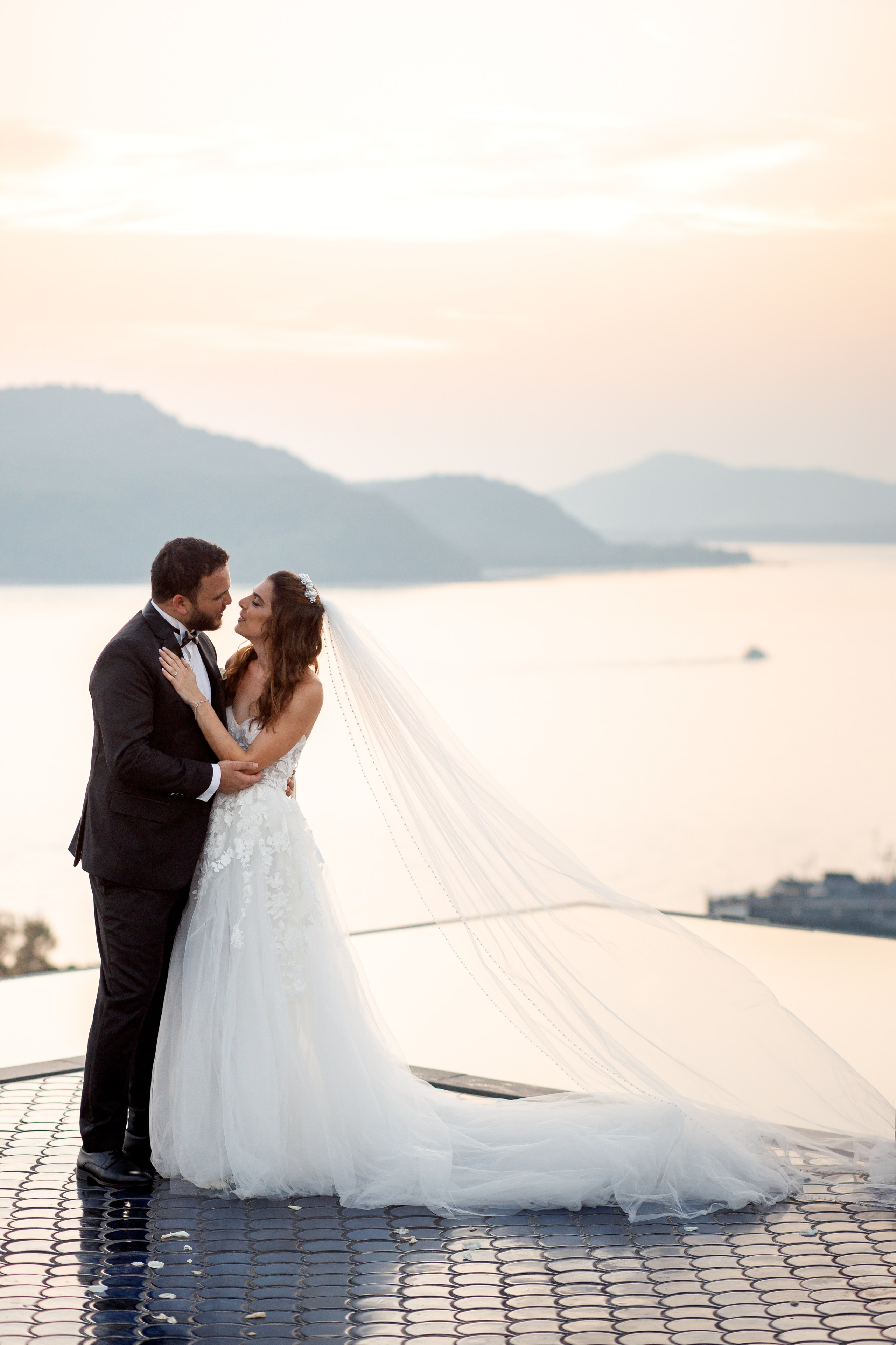 молодожены обнимаются на фоне закатного неба