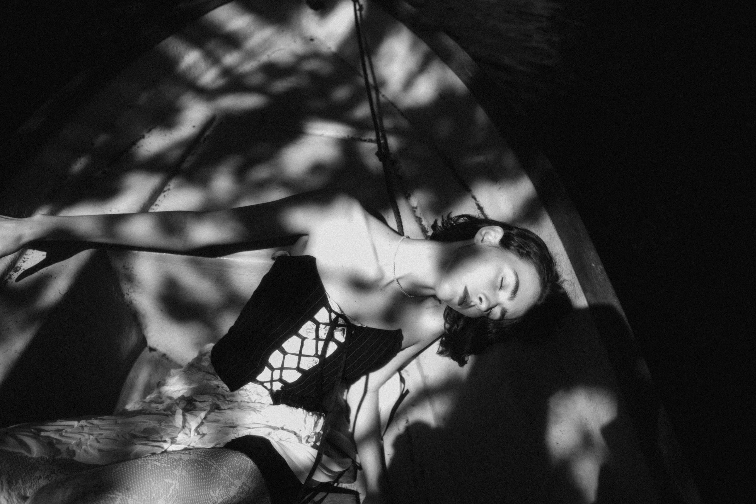 Молодая девушка лежит в лодке в тени от листьев