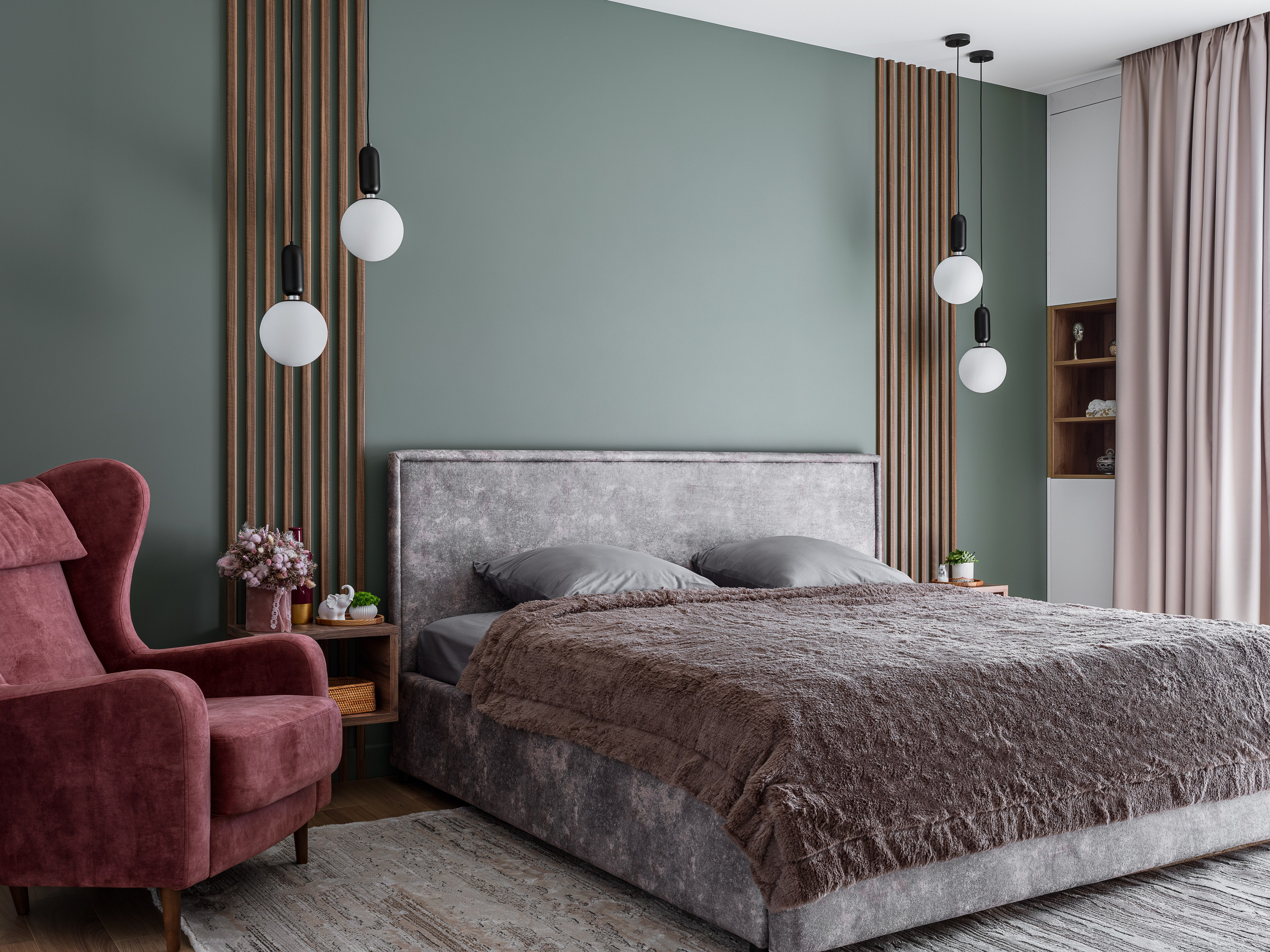 Фото спальни с мягкой серой кроватью, изумрудной акцентной стеной, подвесными светильниками и бордовым креслом, оформленной в современном стиле дизайнерами Алёной Поповой и Анастасией Дмитриевой, снятой фотографом Сергеем Денисенко.