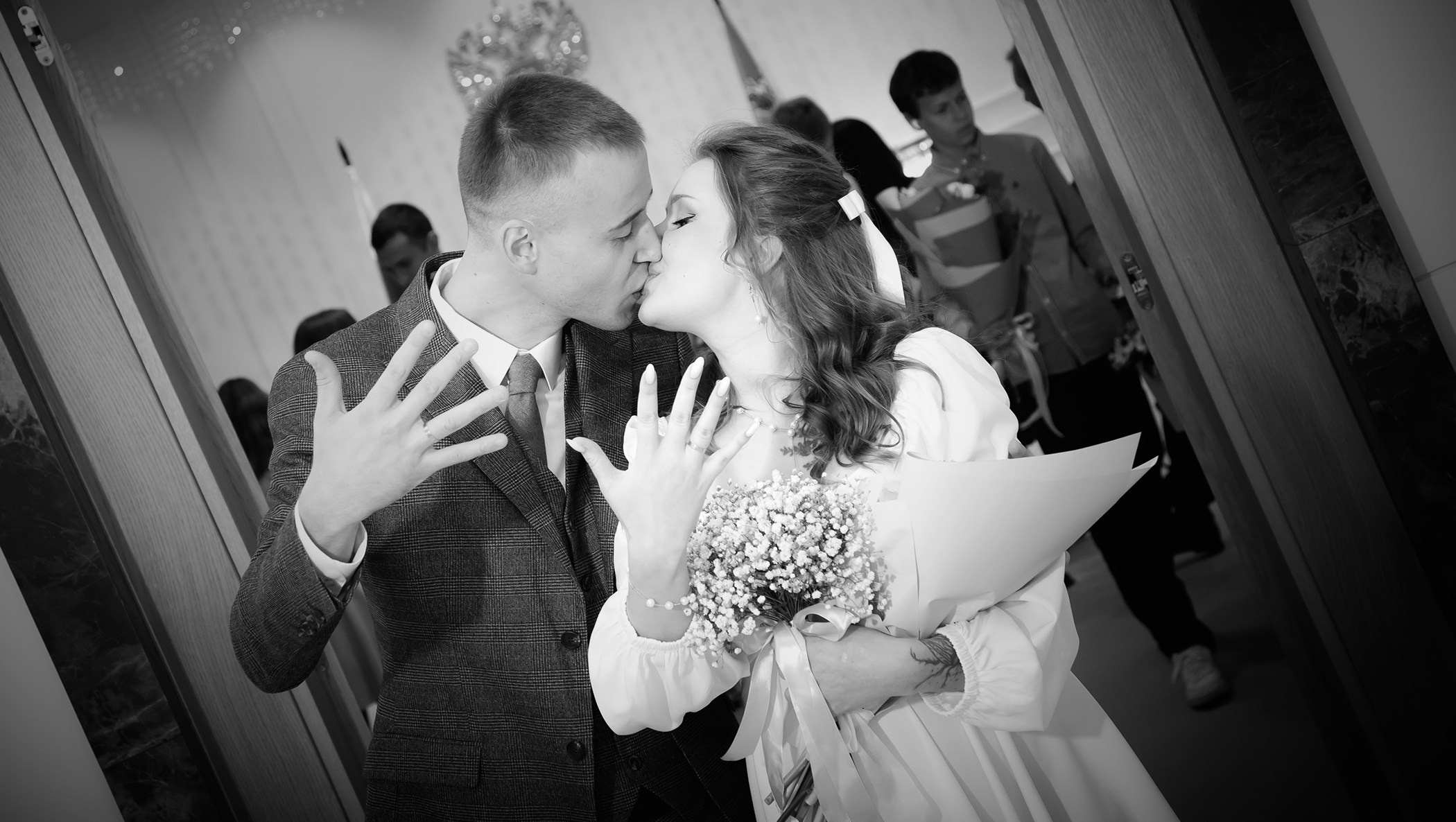 черно белое фото где жених и невеста целуются и показывают руки с кольцами которые только что надели друг другу 