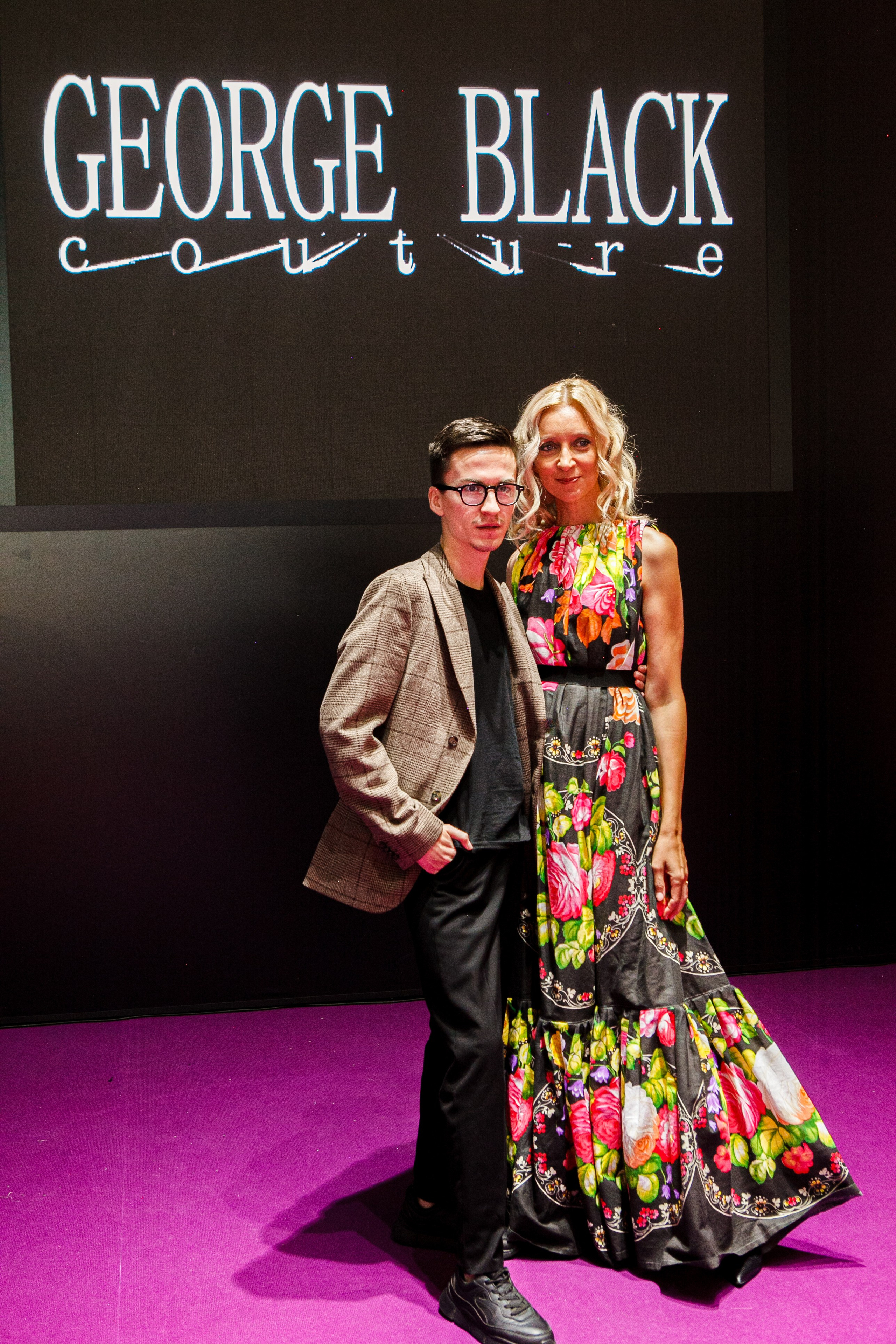  "Модели в ярких нарядах проходят по подиуму во время показа мод, освещенные яркими софитами и окруженные восторженными зрителями."