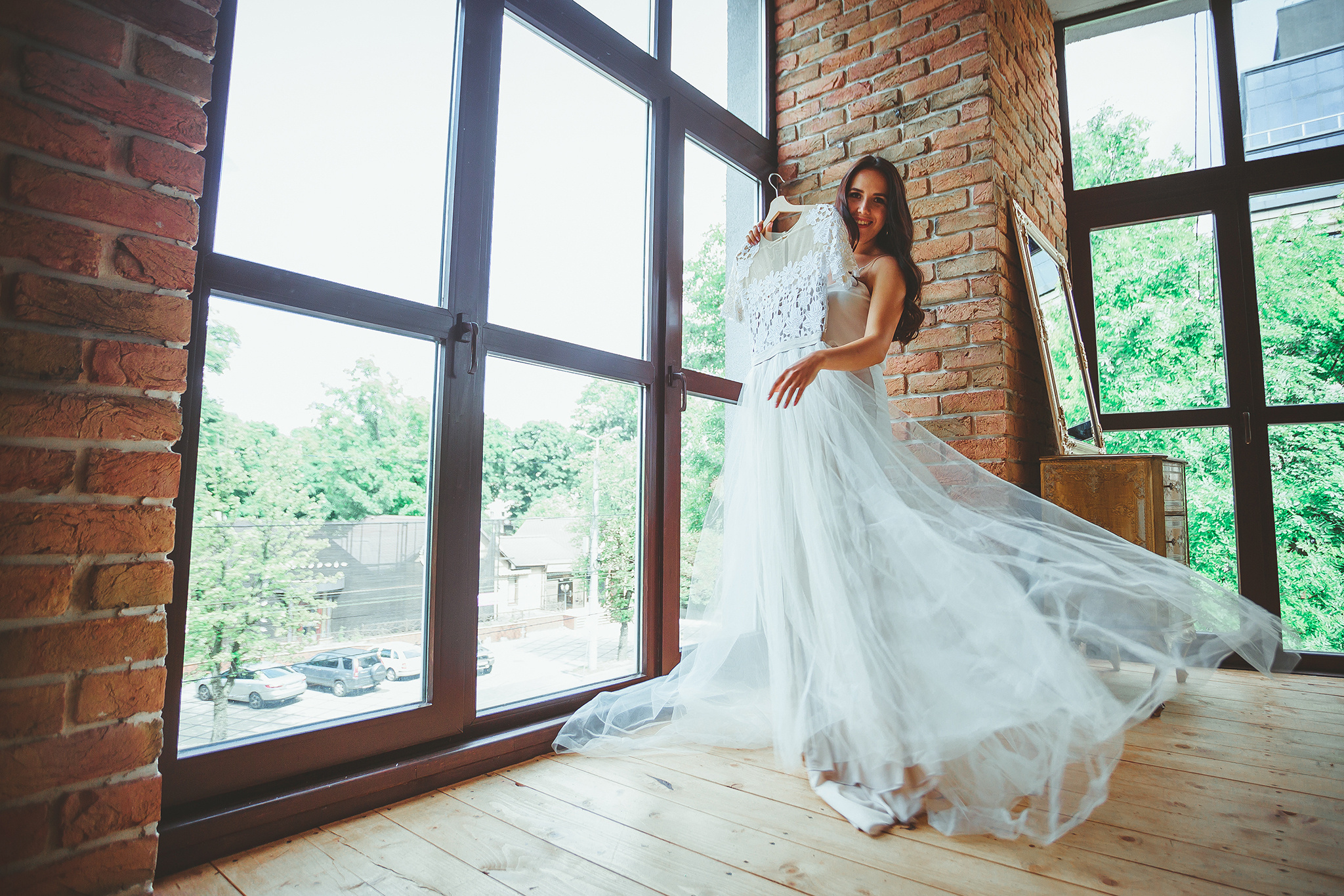 Невеста держит свадебное платье на сборах