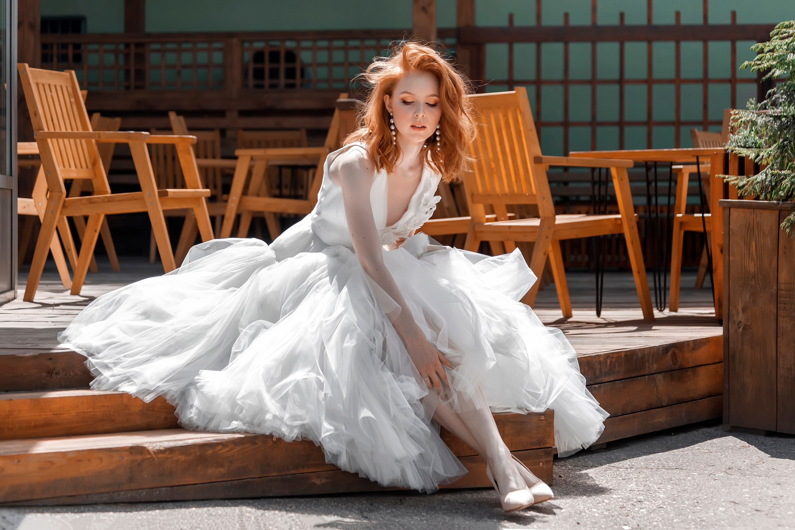 Невеста сидит в летнем кафе и поправляет платье - фотосессия Ульяновск
