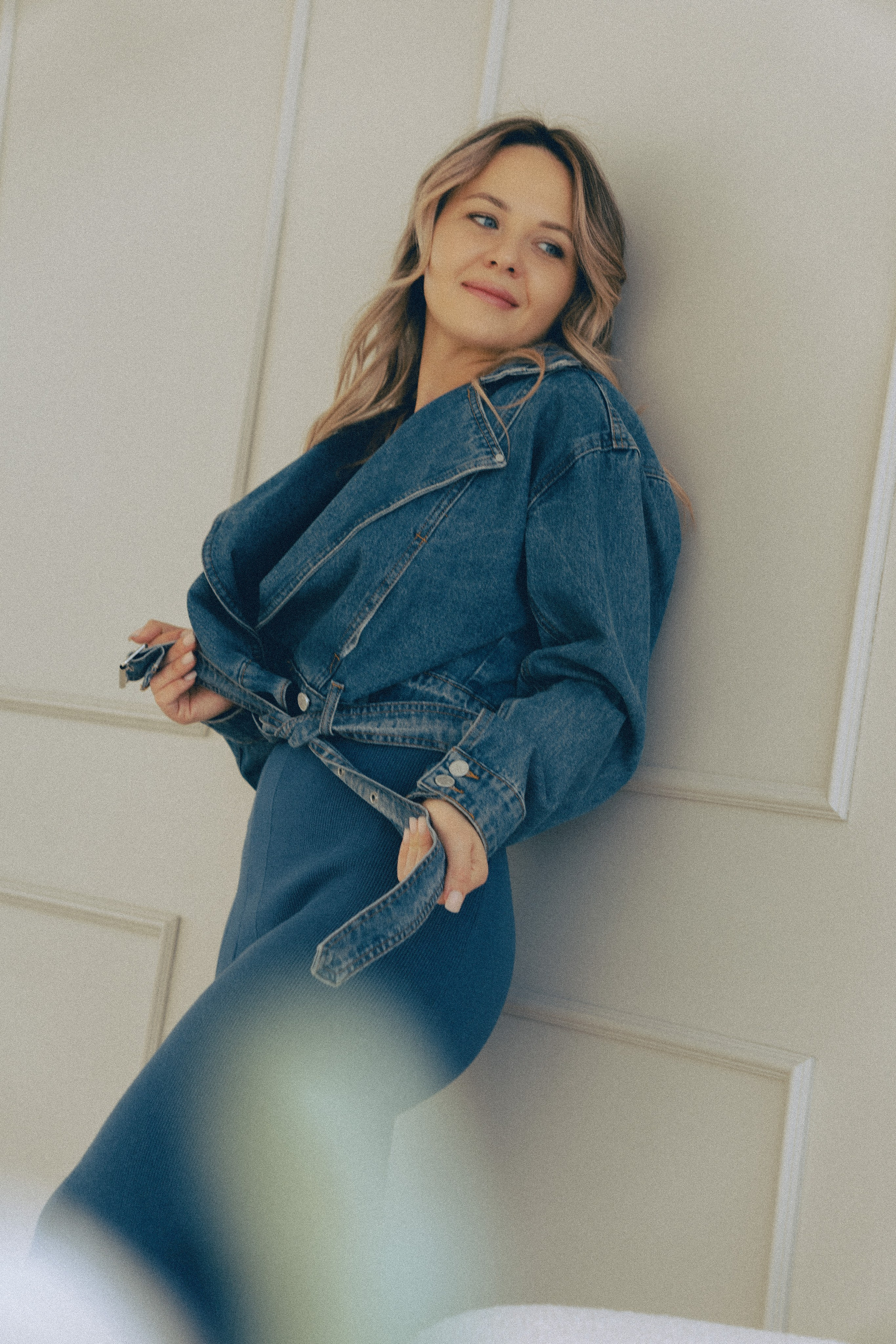 портрет милой девушки около стены в студии с естественным светом