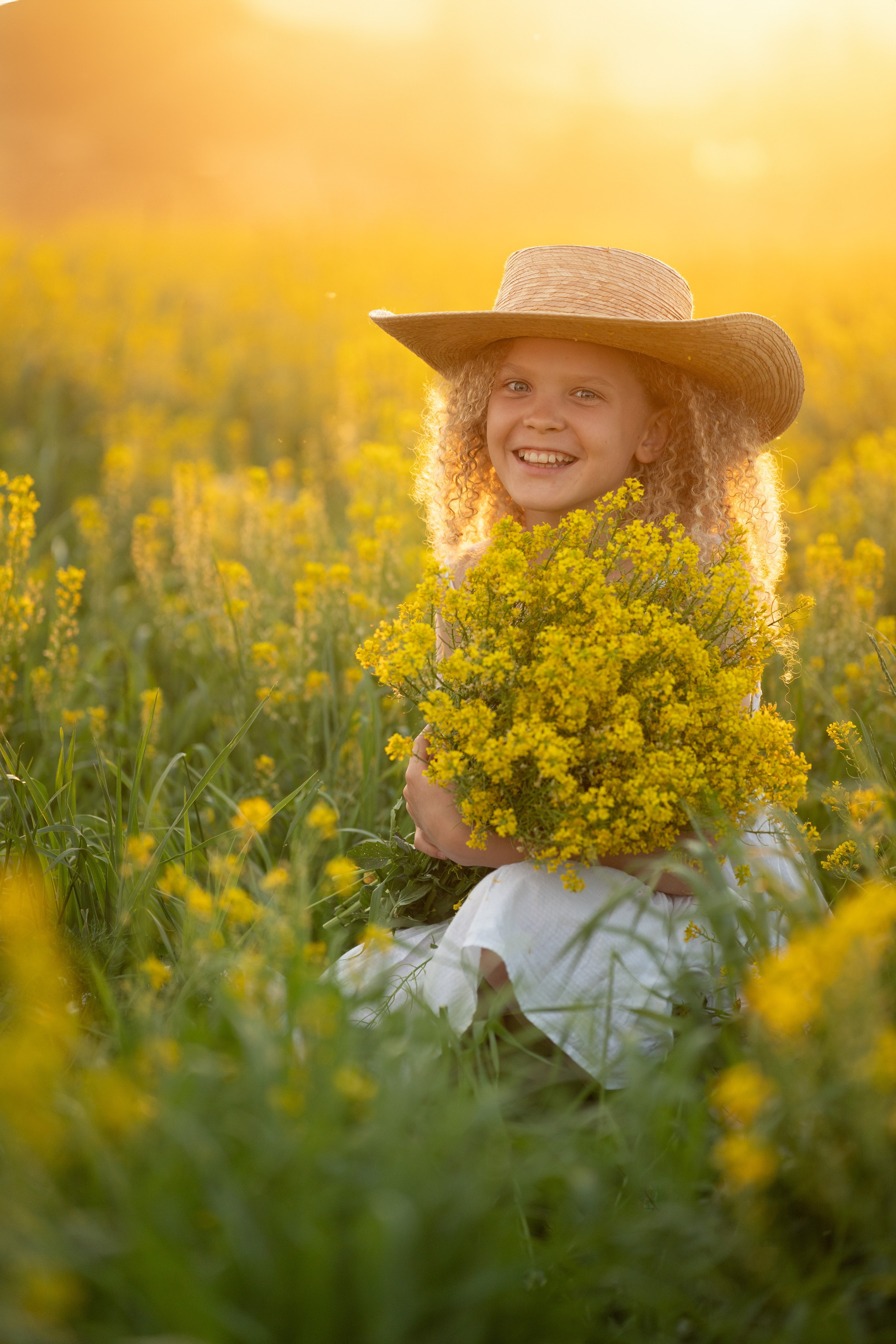 Солнечный портрет ребенка в шляпе на фотосессии в поле. Смеющийся ребенок летом на снимке