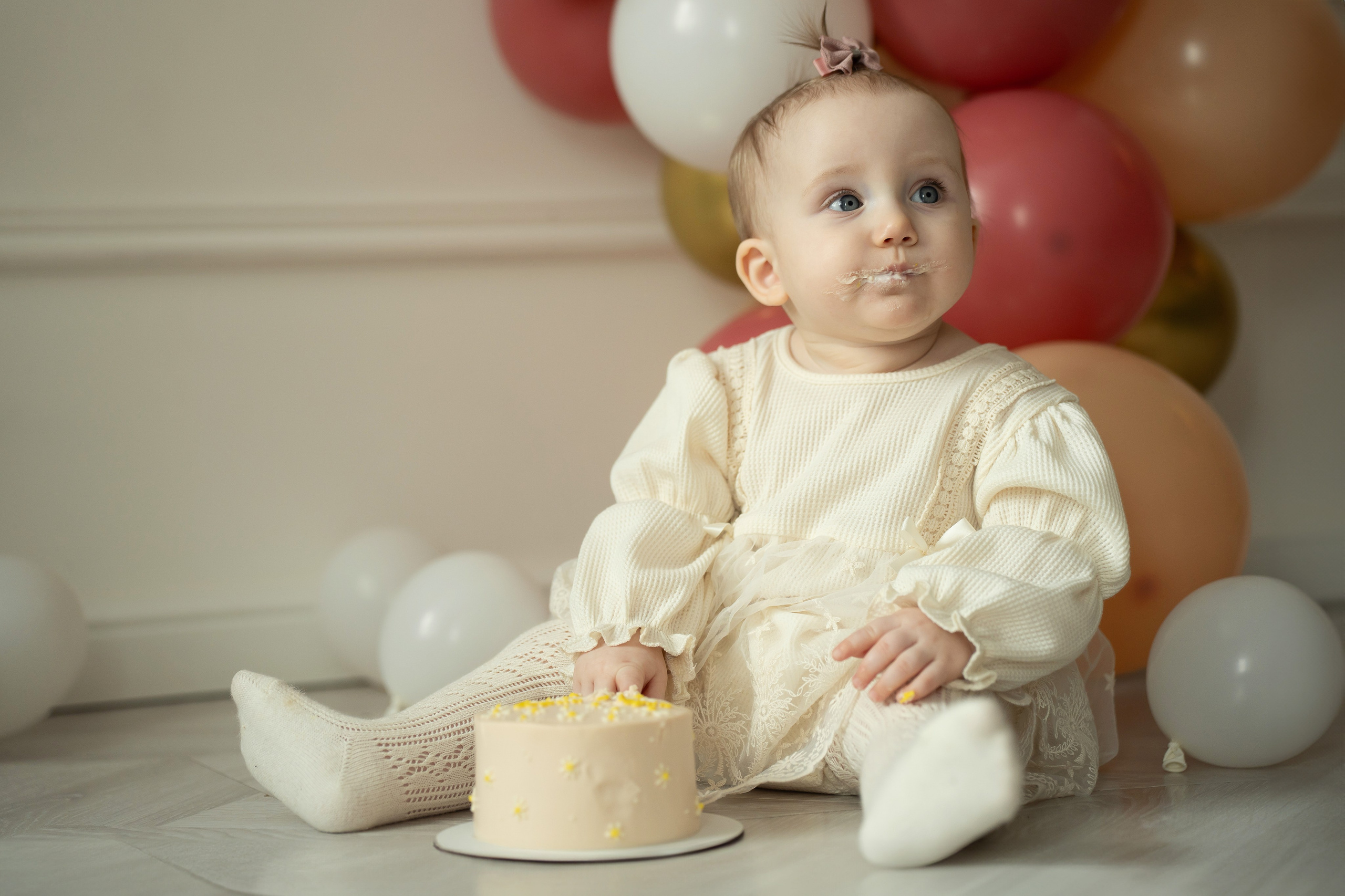 Кадр с малышкой, которая пробует тортик на свой день рождение. Фотосессия на годик в студии. Smash cake фотосессия.
