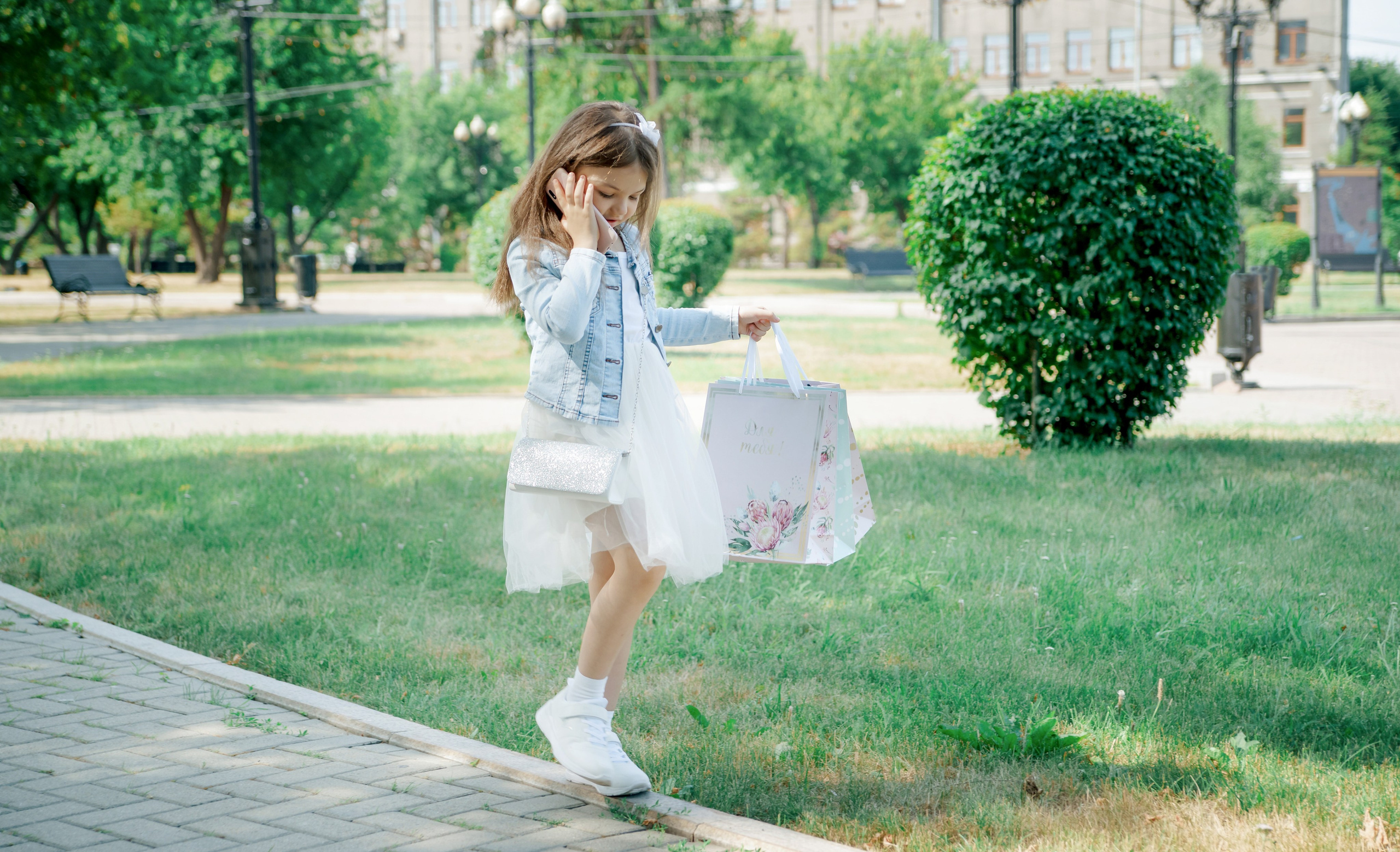 Детская фотосессия летом - девочка идет с покупками и говорит по телефону