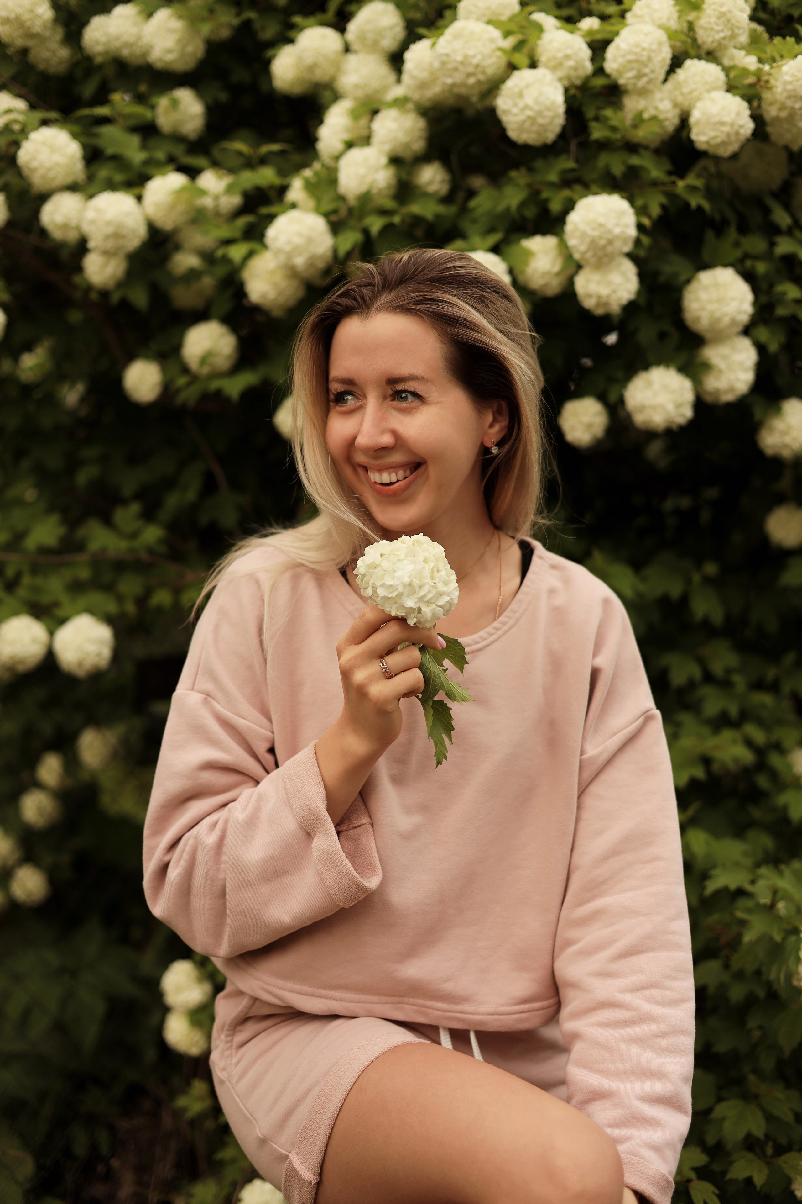 Фотосессия на улице девушка держит букет в руке на фоне цветов