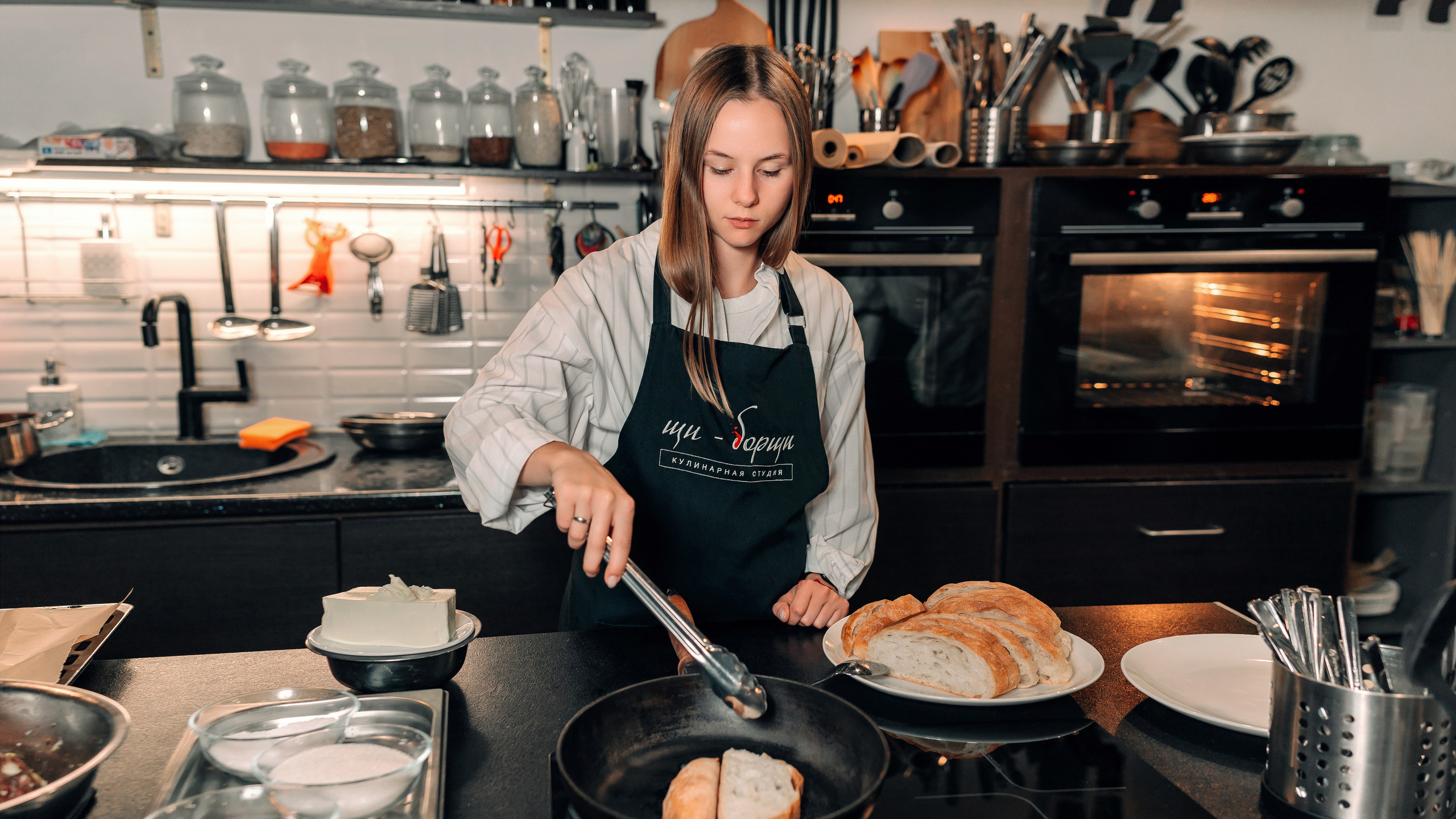 Девушка в фартуке обжаривает хлеб для салата. Фотосессия кулинарного мастер класса в Воронеже.