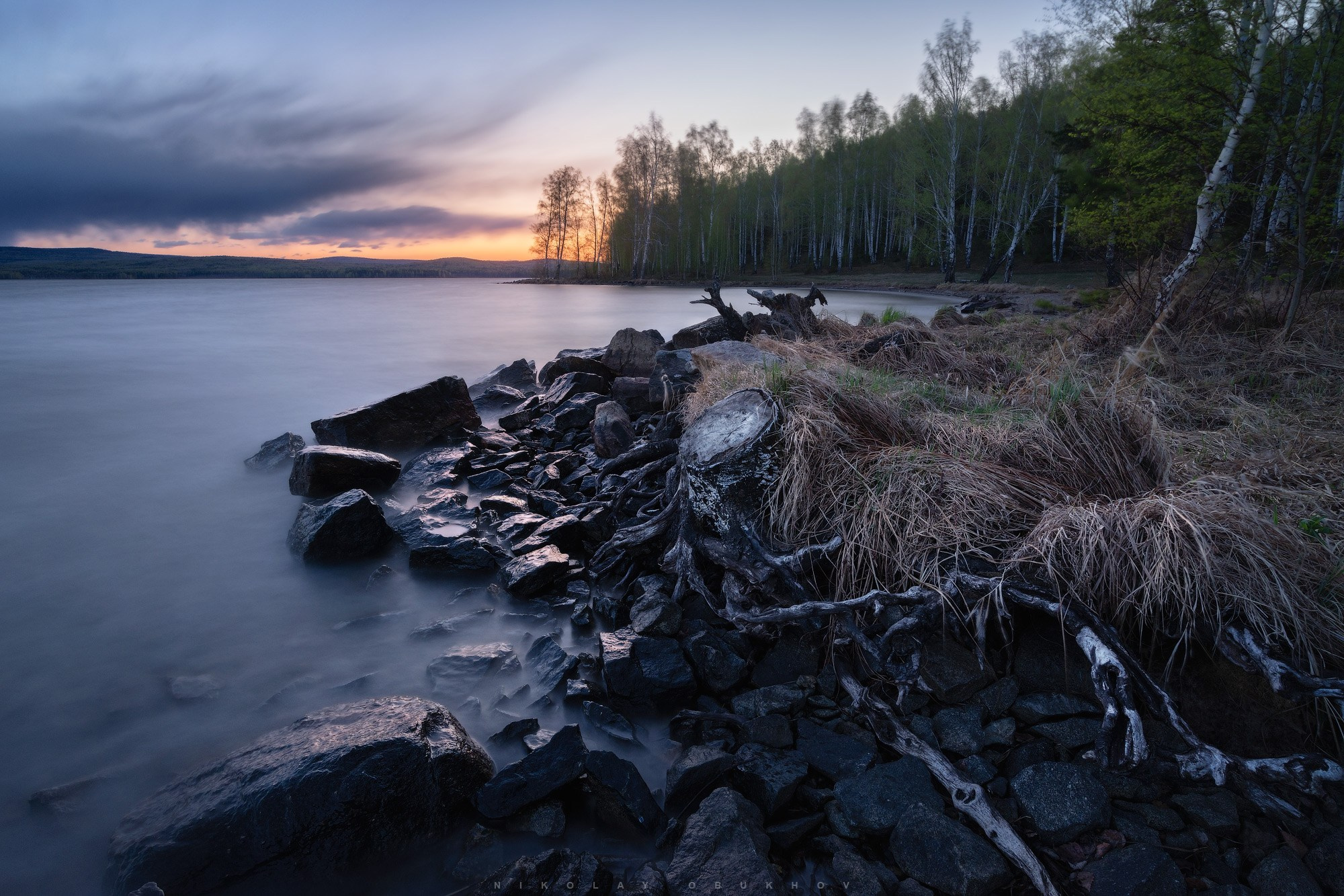 Коряга на берегу Черноисточинского пруда. Фото на длинной выдержке, вода размыта