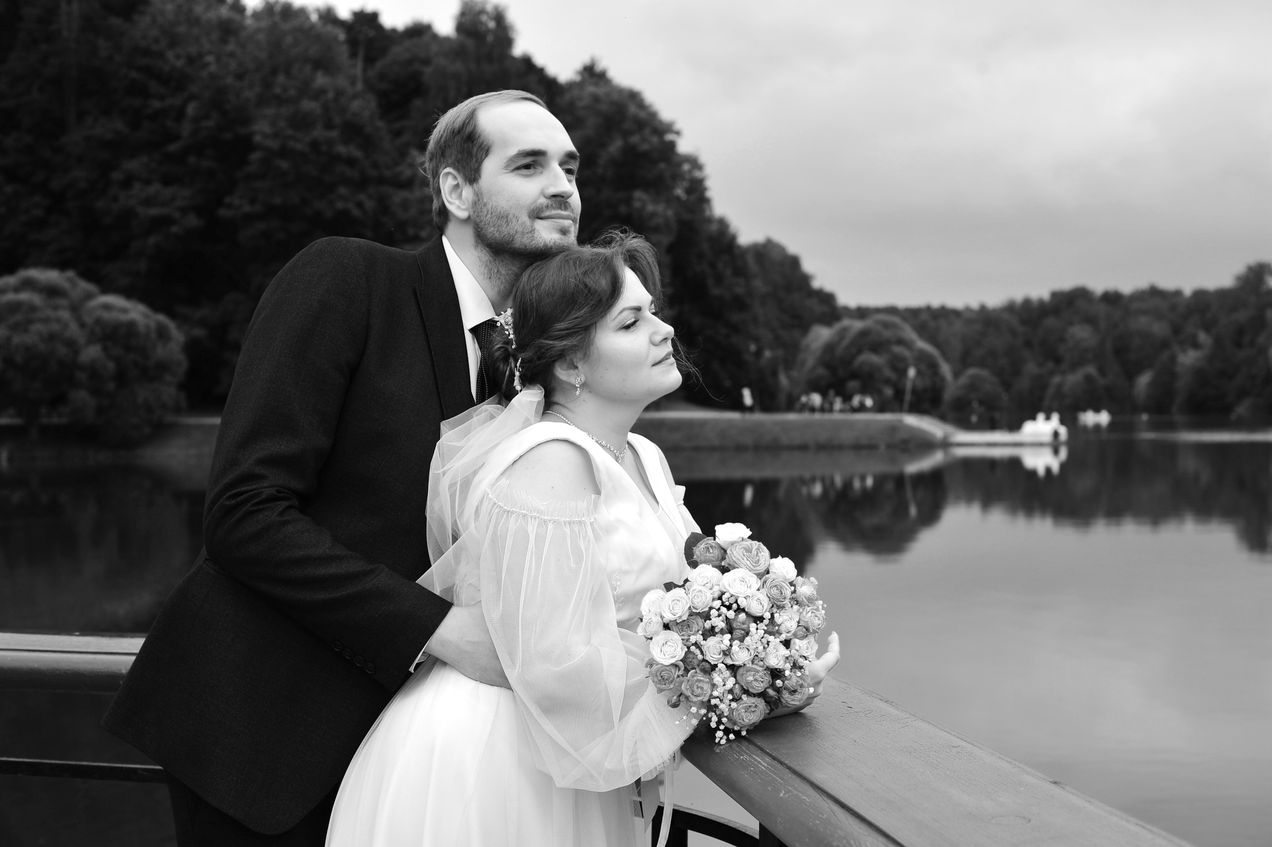 Свадьба в Царицыно пасмурным летним днем, молодожены стоят рядом и смотрят на воду пруда в парке,  черно-белая фотография