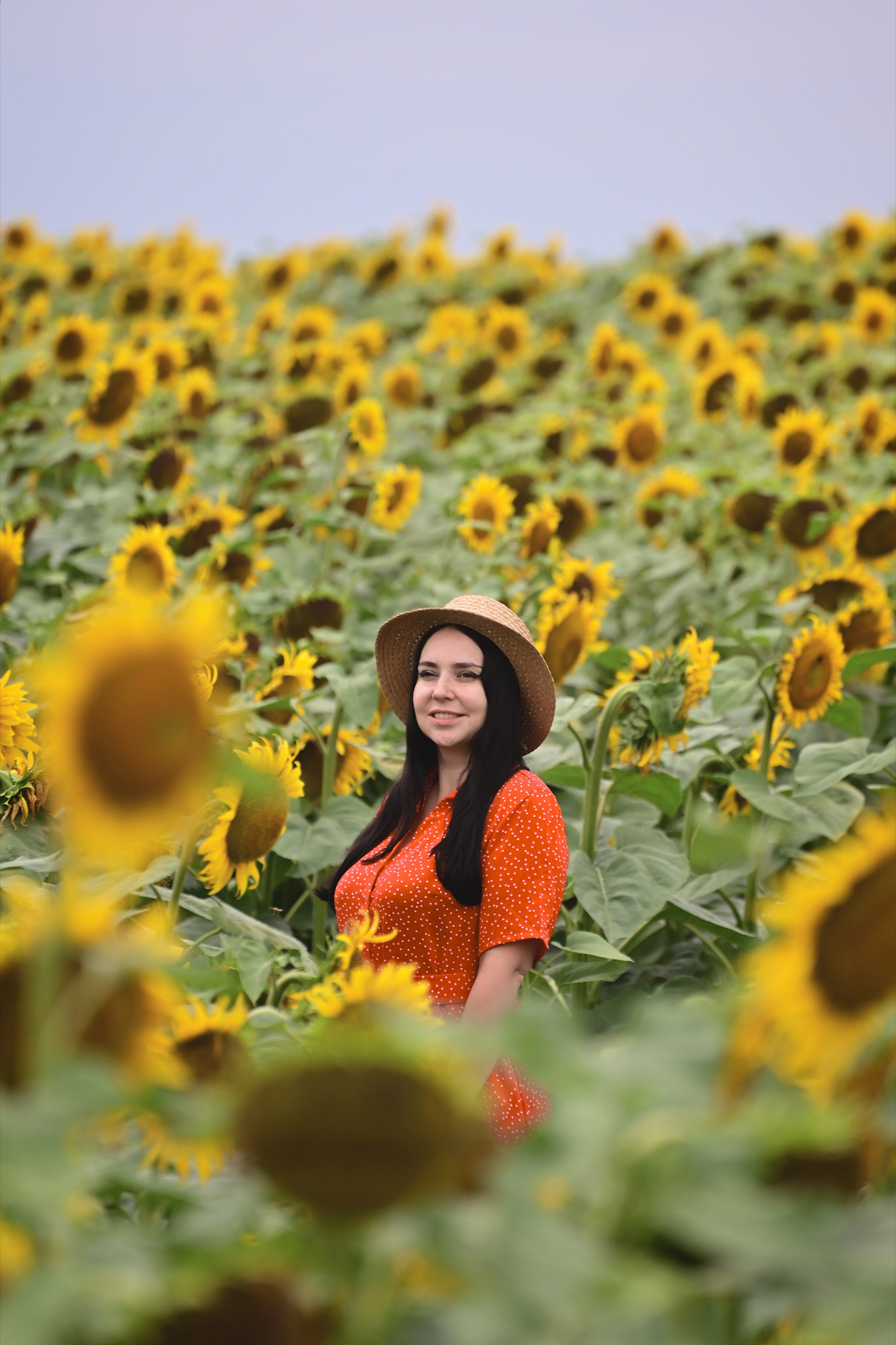 Девушка в шляпе в поле с подсолнухами