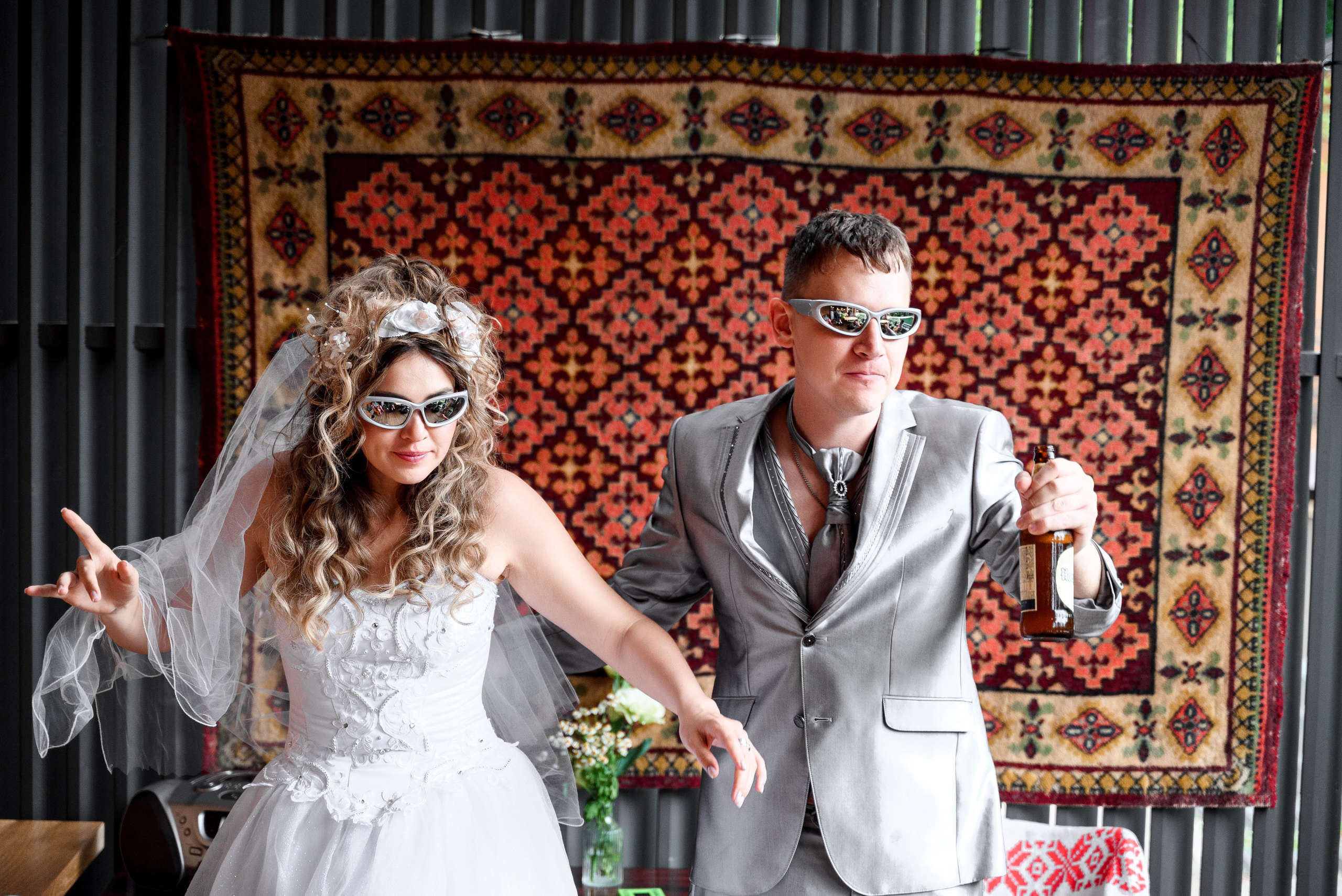 Ностальгия по 90-м в Сочи: уникальная свадьба с атмосферой тех лет муж и жена с бутылками пива на фоне ковра  в очках 