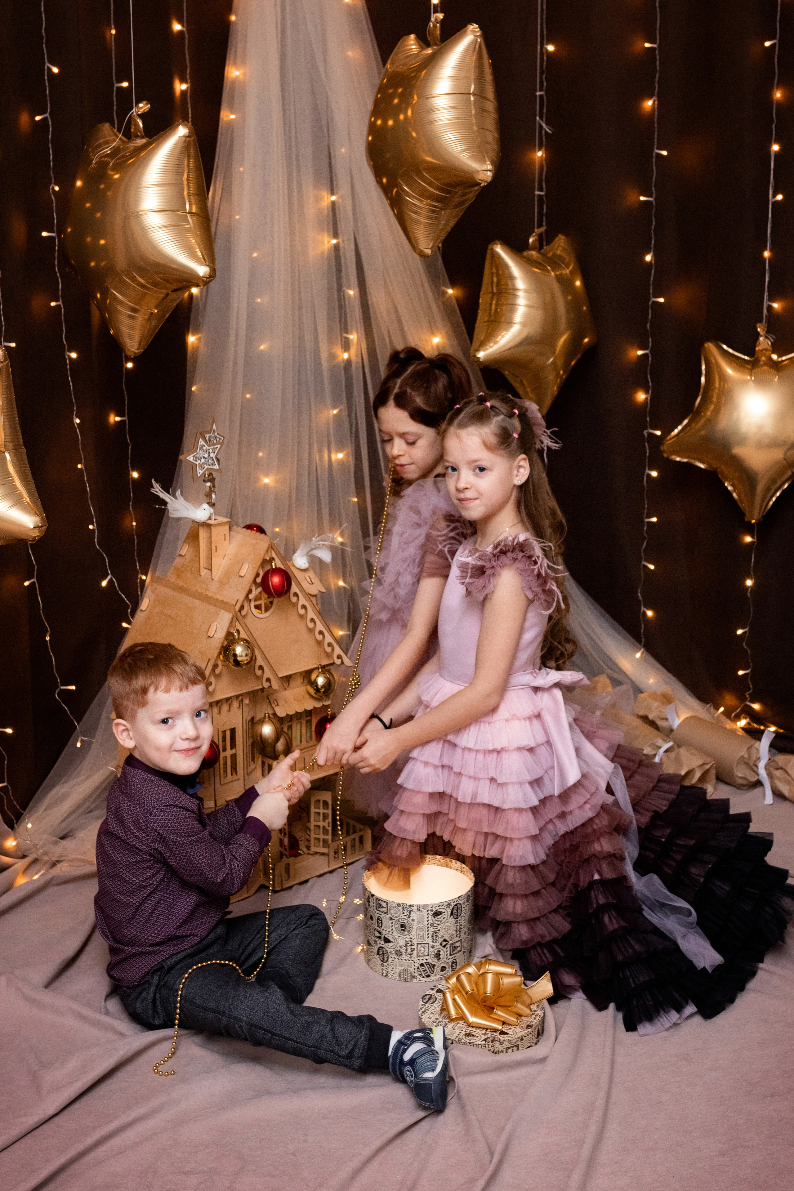 украшают новогодний домик шарами и гирляндой