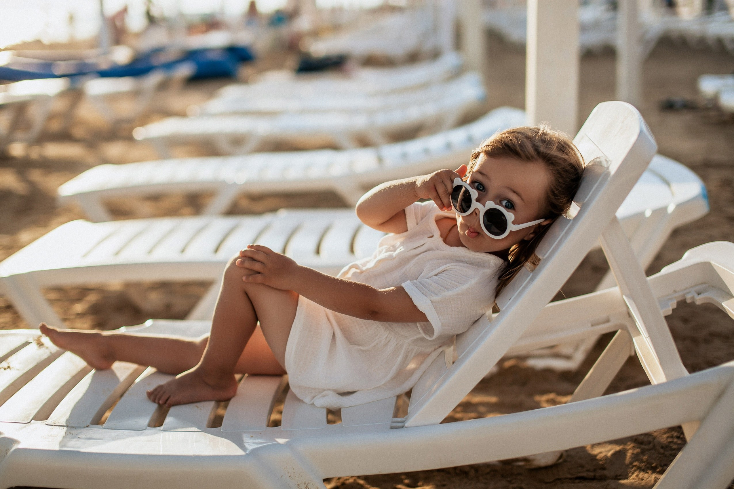Девочка в солнечных очках на шезлонге на пляже Джемете.