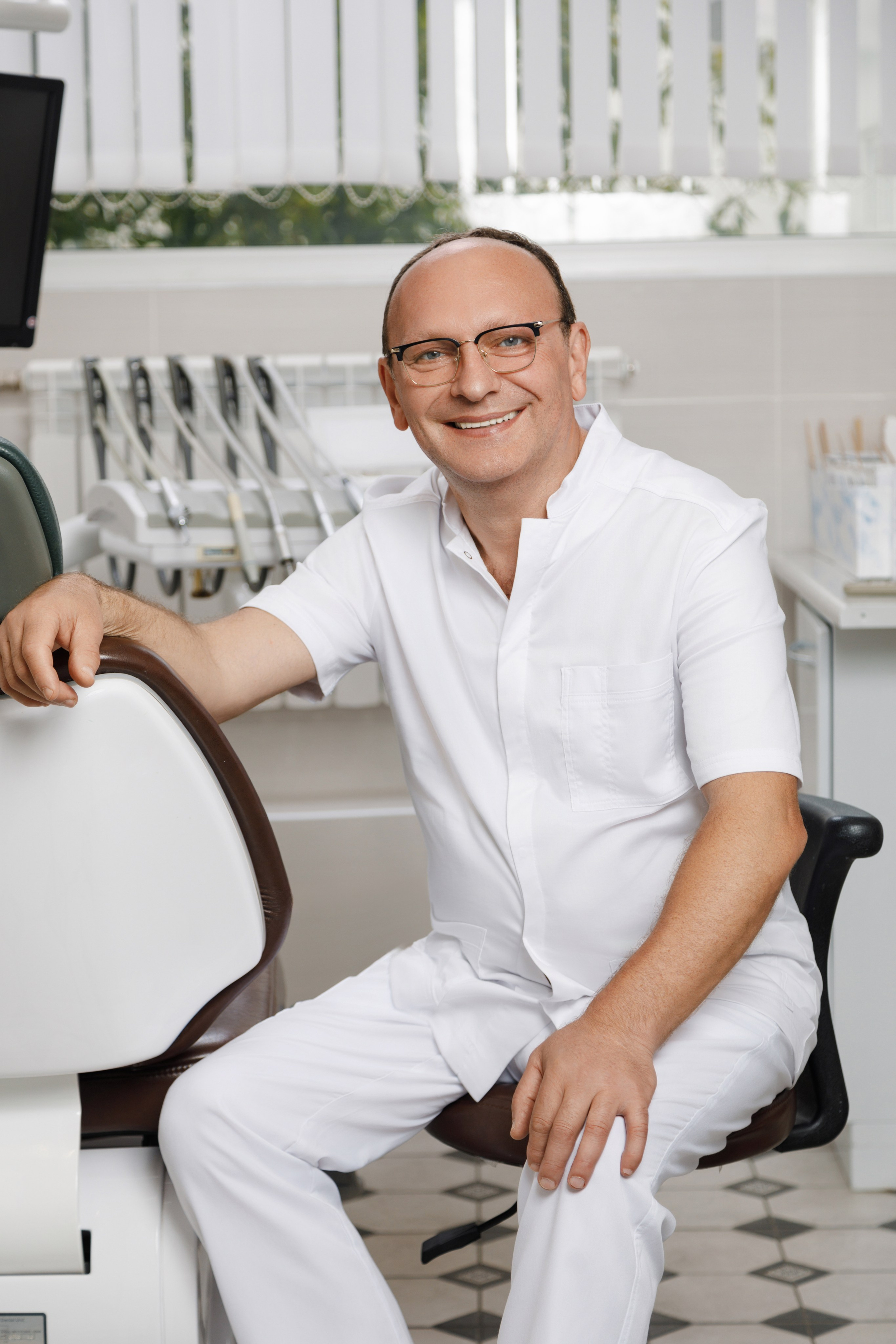 Портрет стоматолога в его рабочем кабинете на фоне стоматологического оборудования.