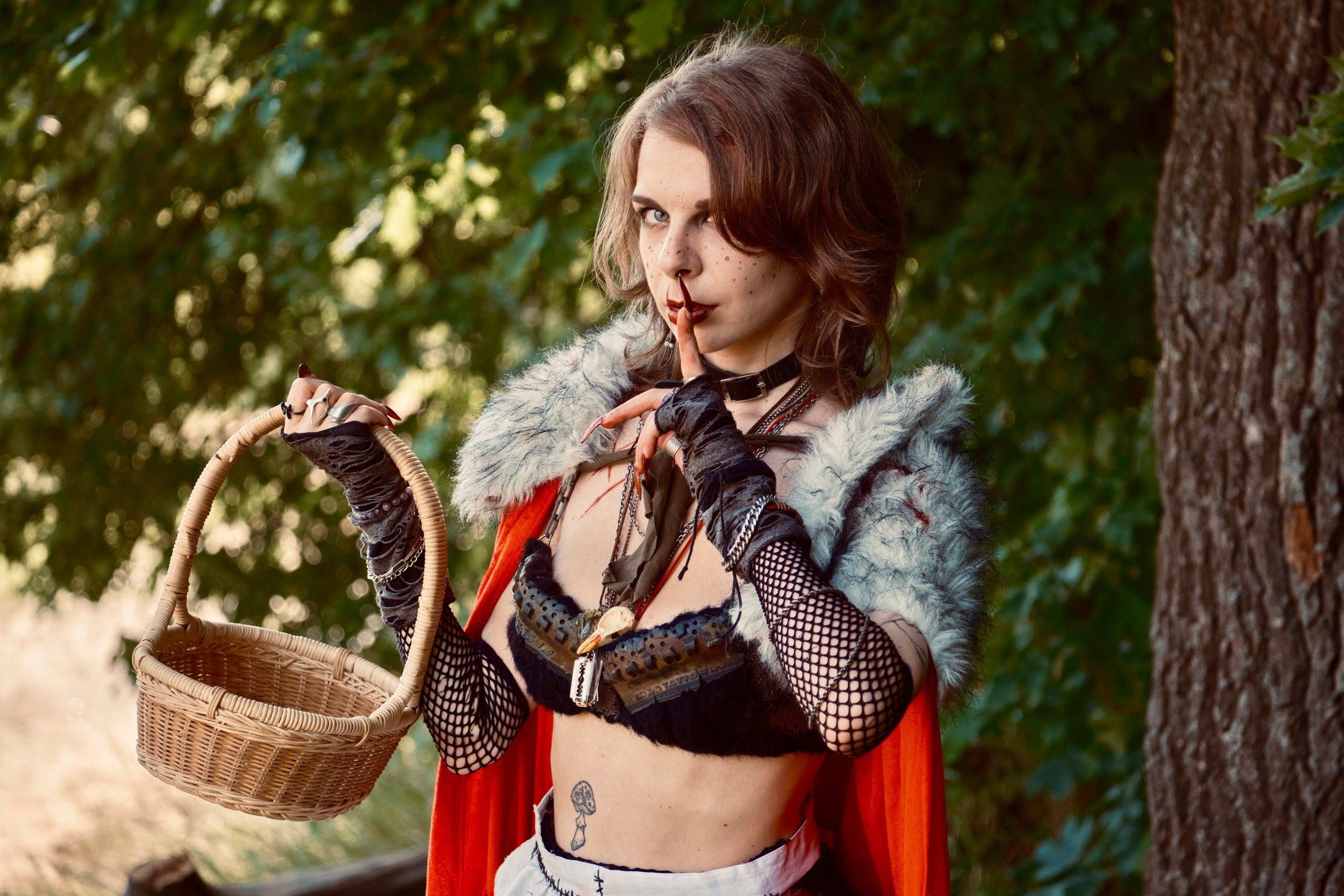 Девушка в красном плаще с корзиночкой гуляет в лесу