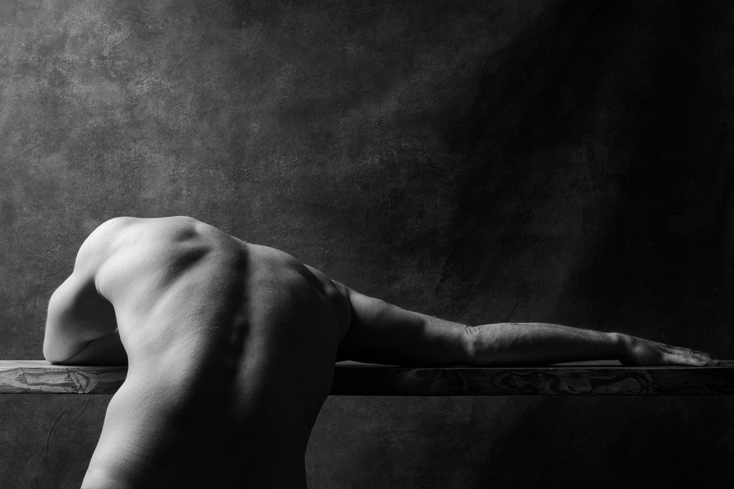 Мужская ню фотосессия в студии, мужчина стоит спиной на против окна 