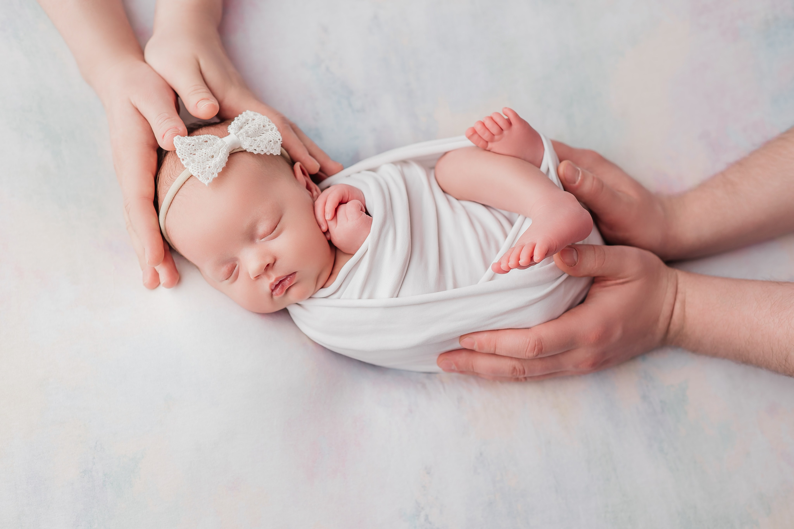 Новорожденная малышка и руки родителей на белом фоне