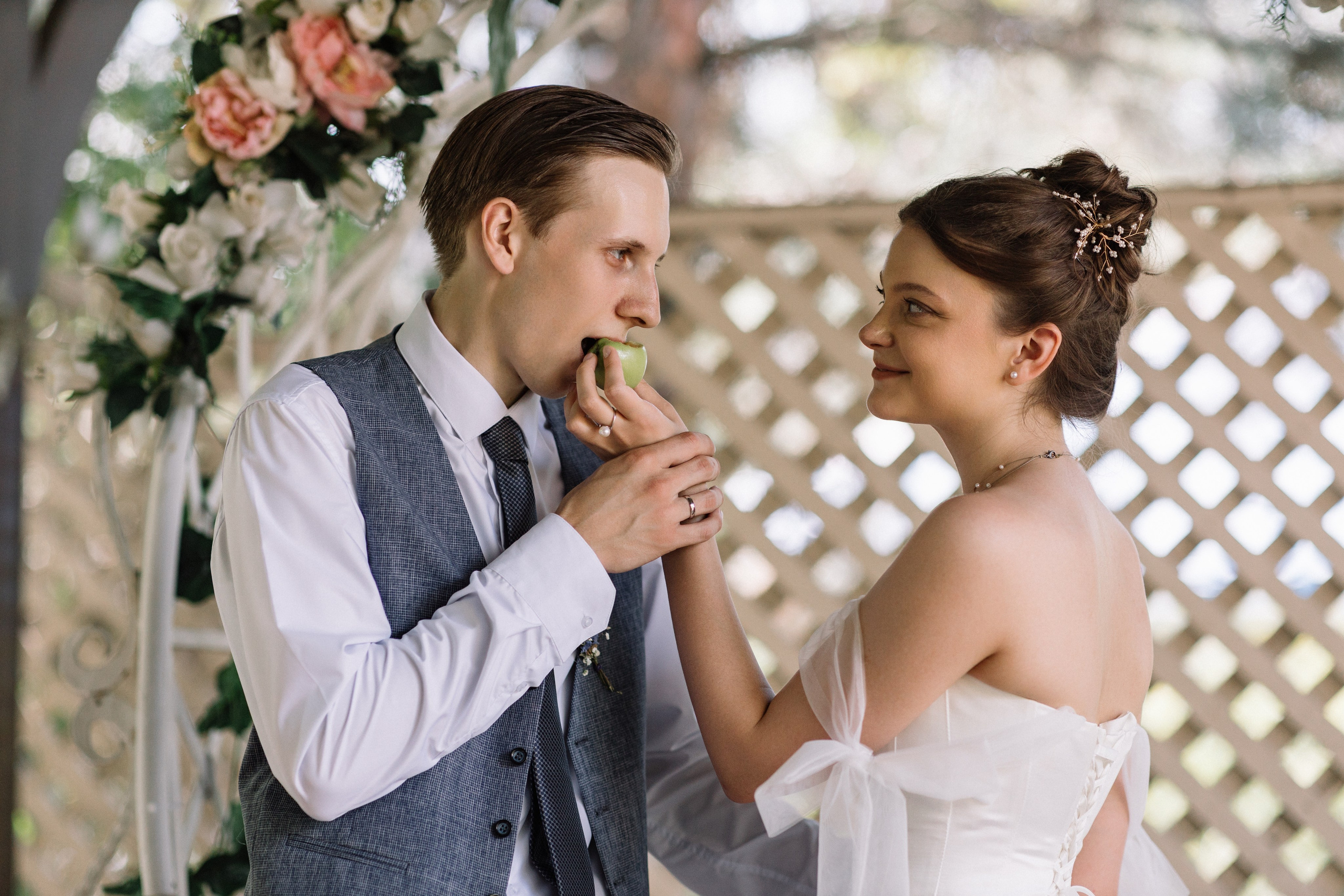 Образный кадр: невеста смотрит в сторону, жених держит за руку.