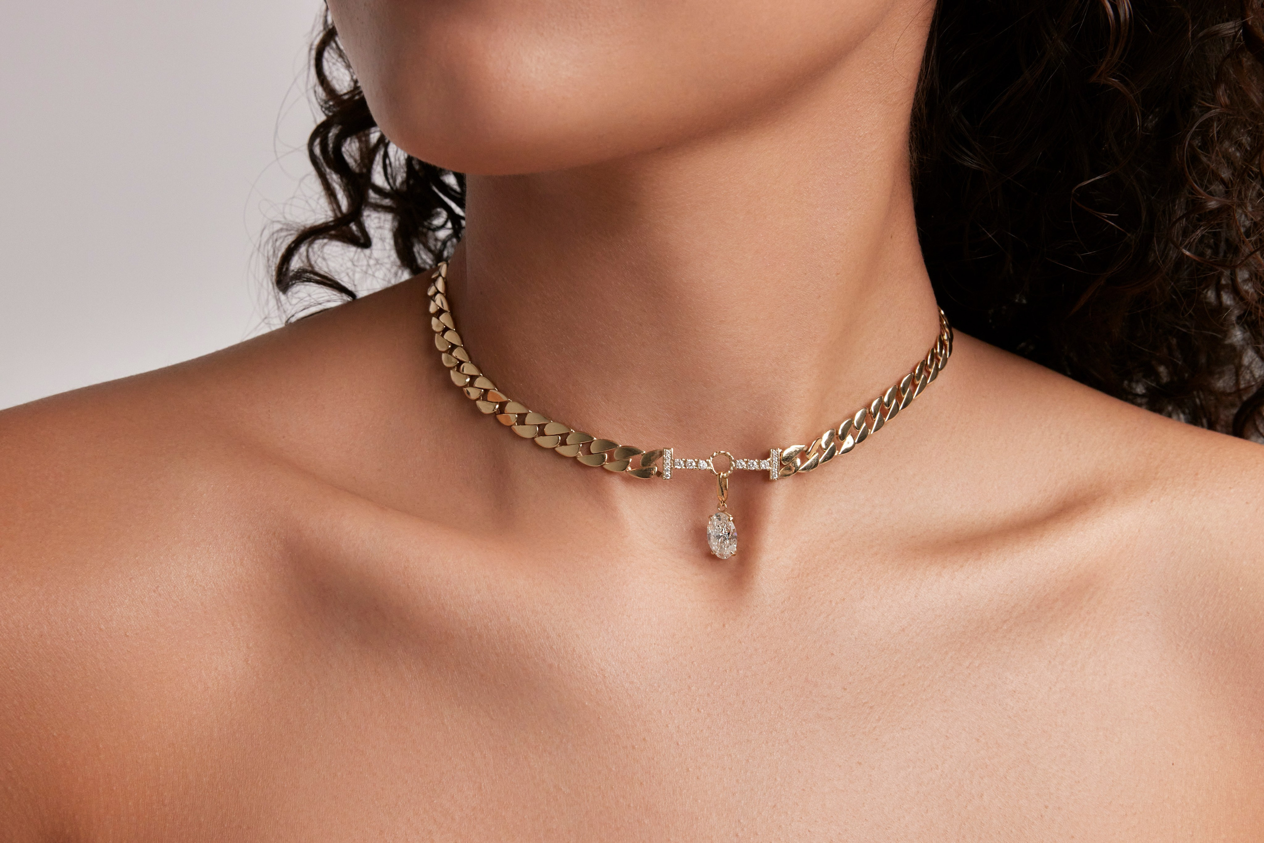 Close-up of a gold necklace with a pendant, styled elegantly on a model's neck.