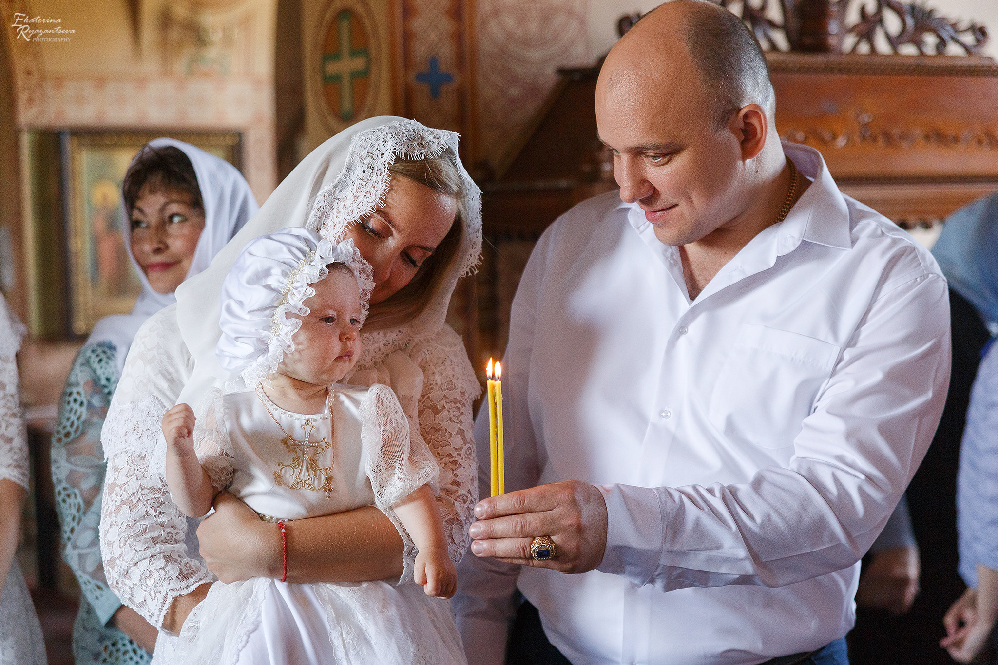 крёстные показывают ребёнку свечку в церкви
