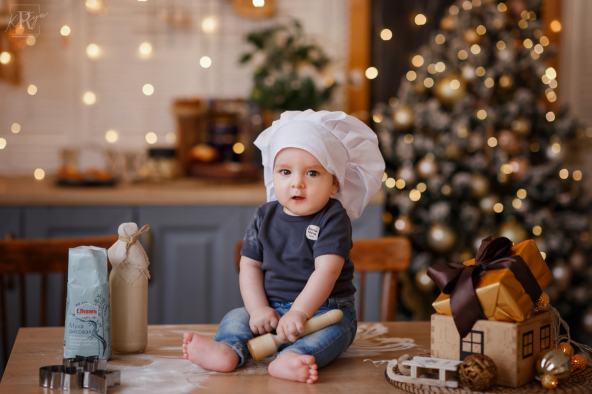 маленький поварёнок в колпаке сидит на столе с мукой