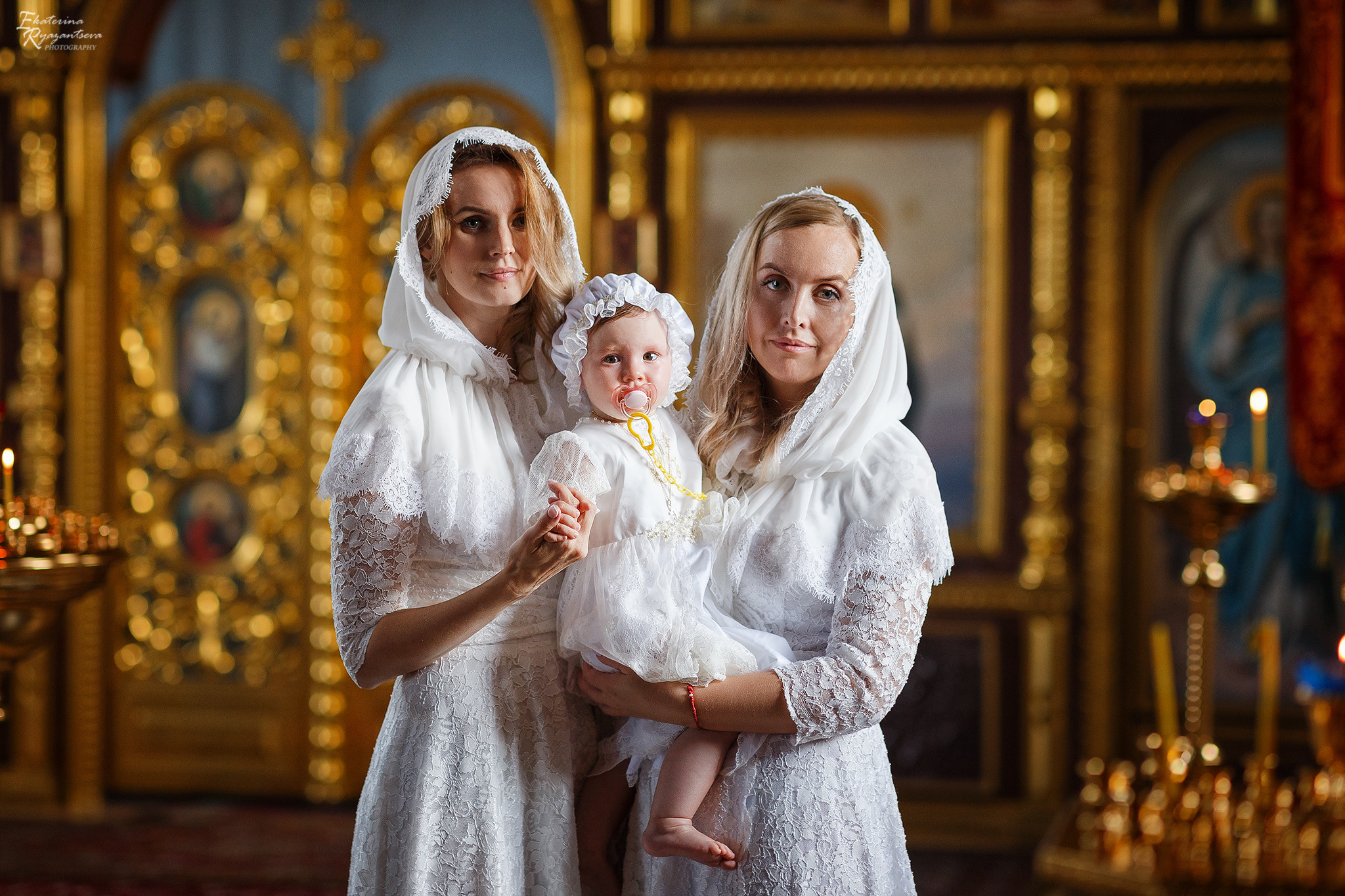 мама и крёстная держат ребенка