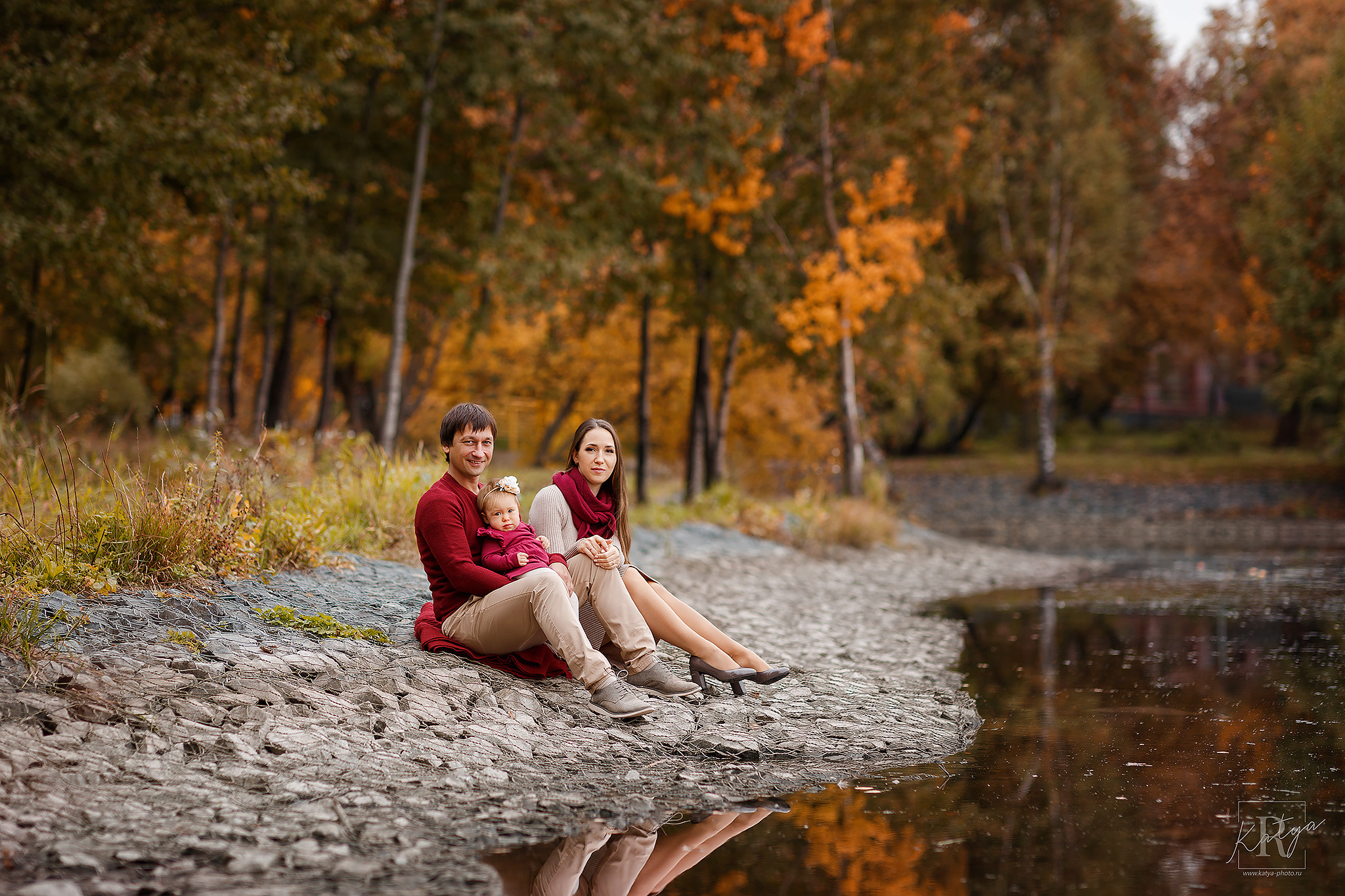семья сидит на берегу в осеннем парке