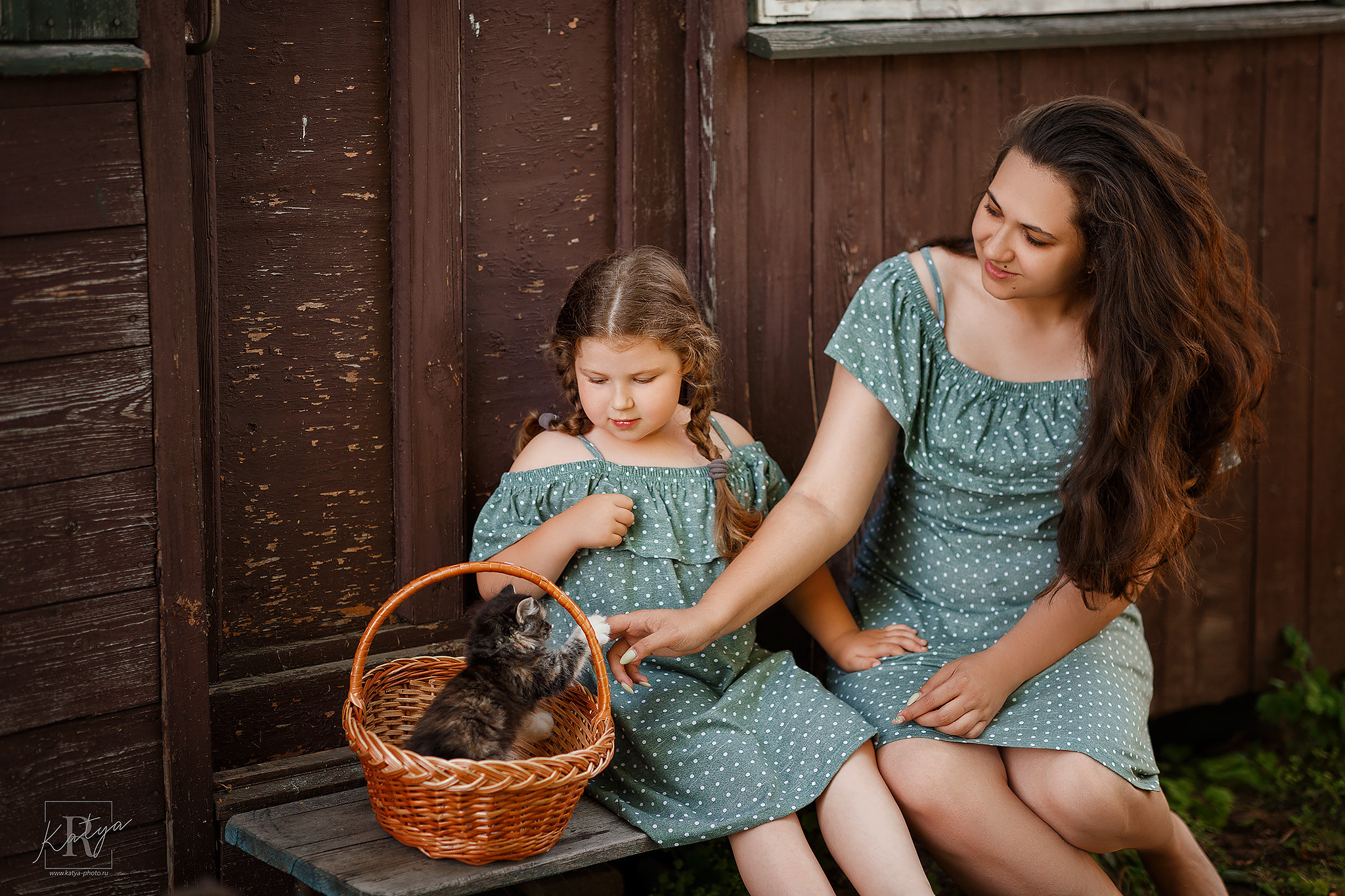 мама и дочка смотрят на котенка в корзине