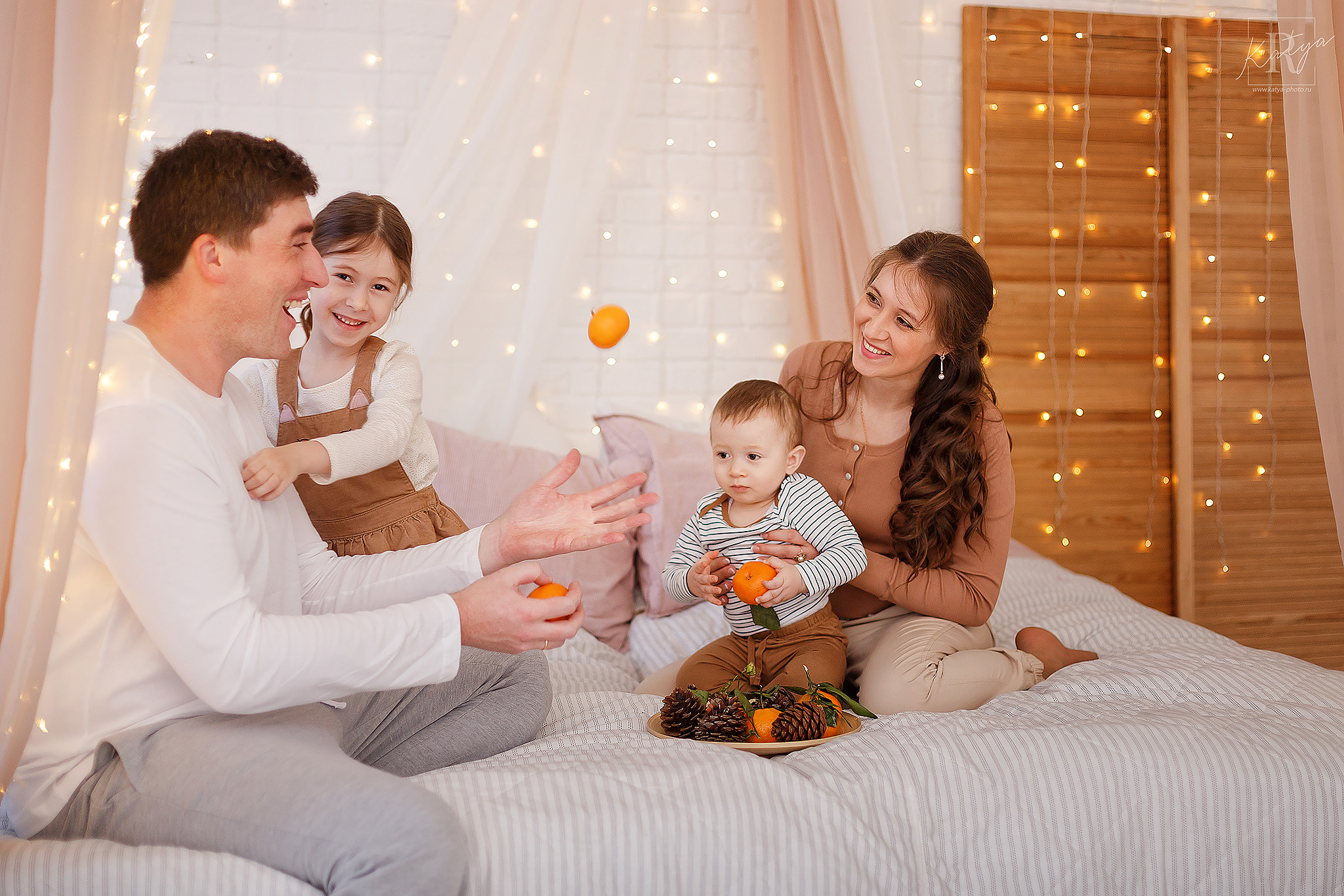 семья играет мандаринами на кровати
