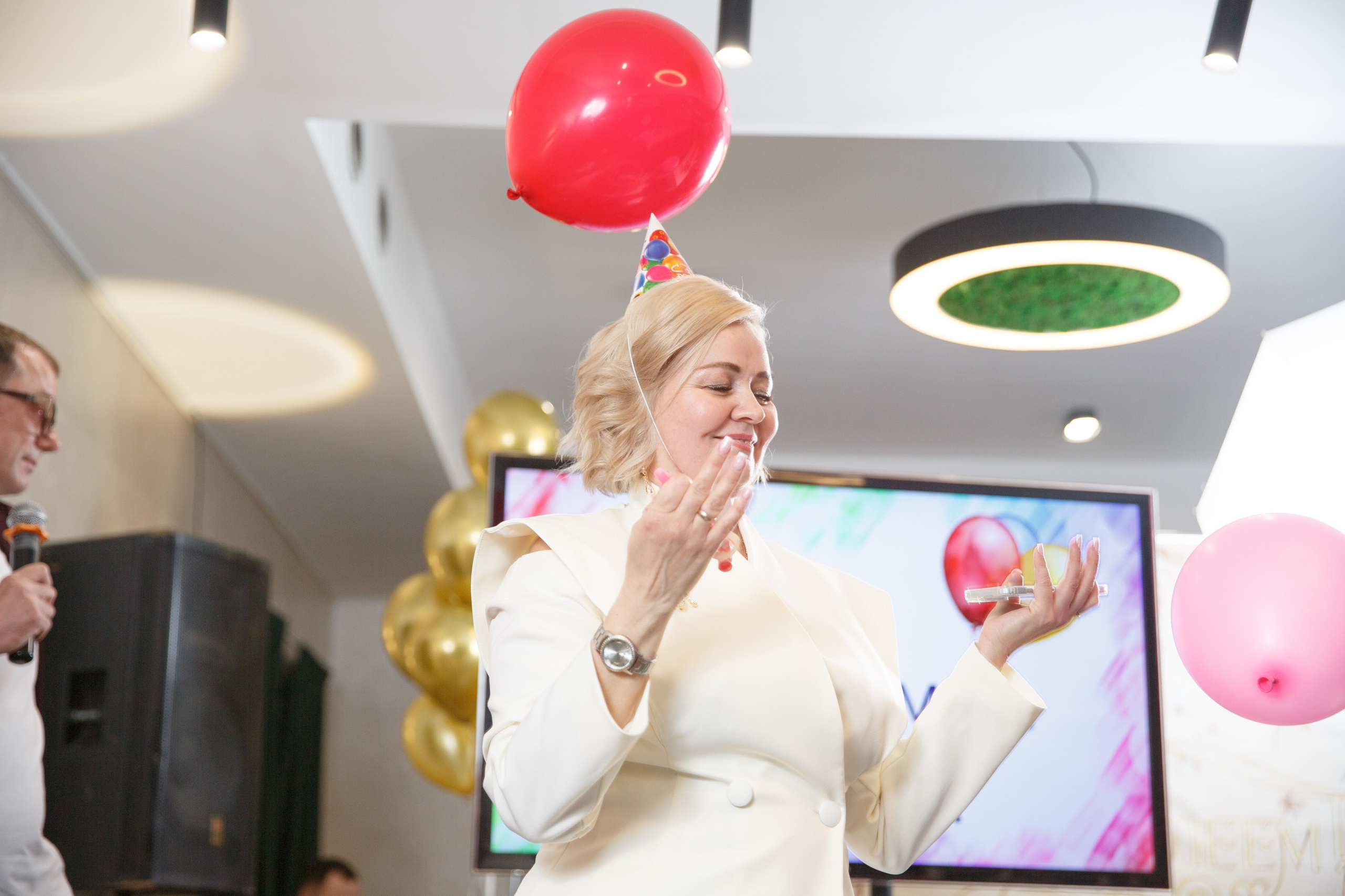 Женщина с розовым воздушным шаром принимает поздравления.