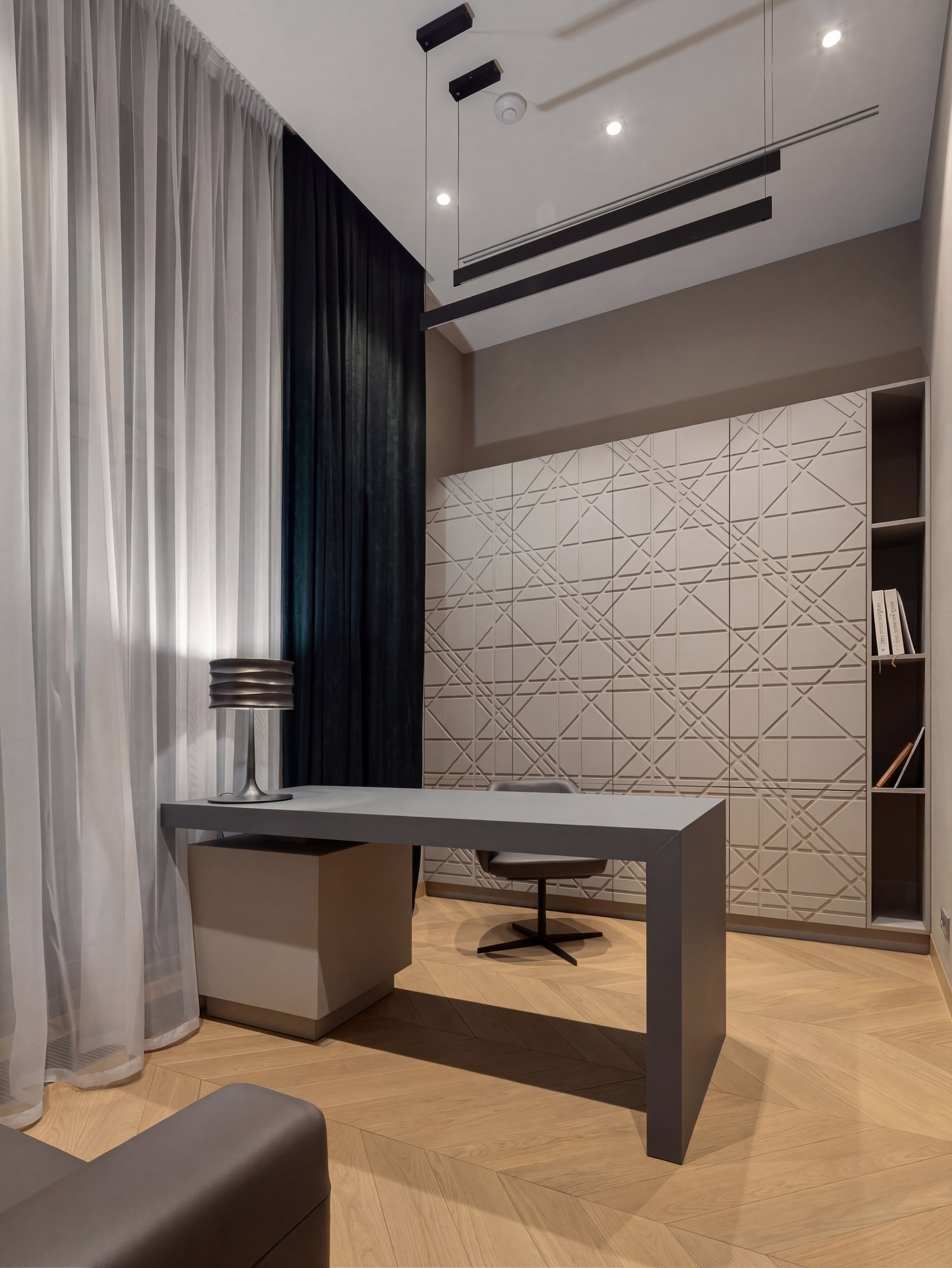 Дизайн кабинета от Валерии Котович: рабочий стол графитового цвета, шкаф с геометрическим рельефом на фасадах, линейные черные светильники и паркет «французская елка» в современном интерьере.