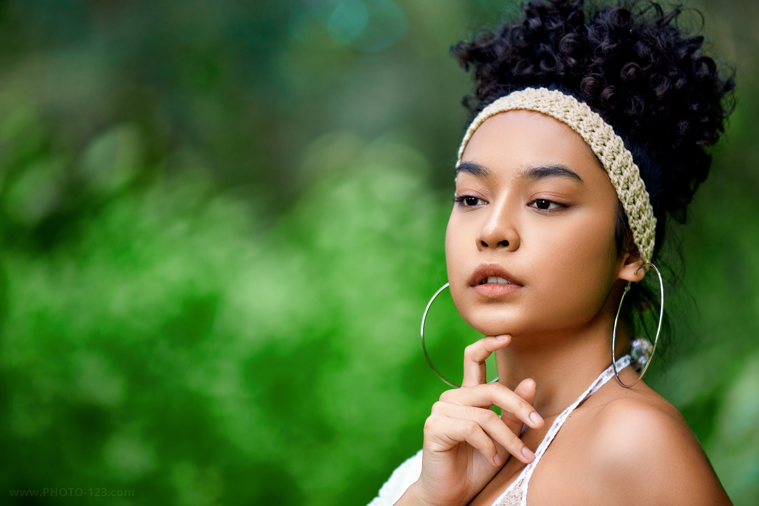 Natural light beauty portrait of a woman with minimal makeup, photographed outdoors against a soft green background, featuring clean skin tones, elegant styling, and calm editorial mood. Professional beauty photography in Phu Quoc, Vietnam