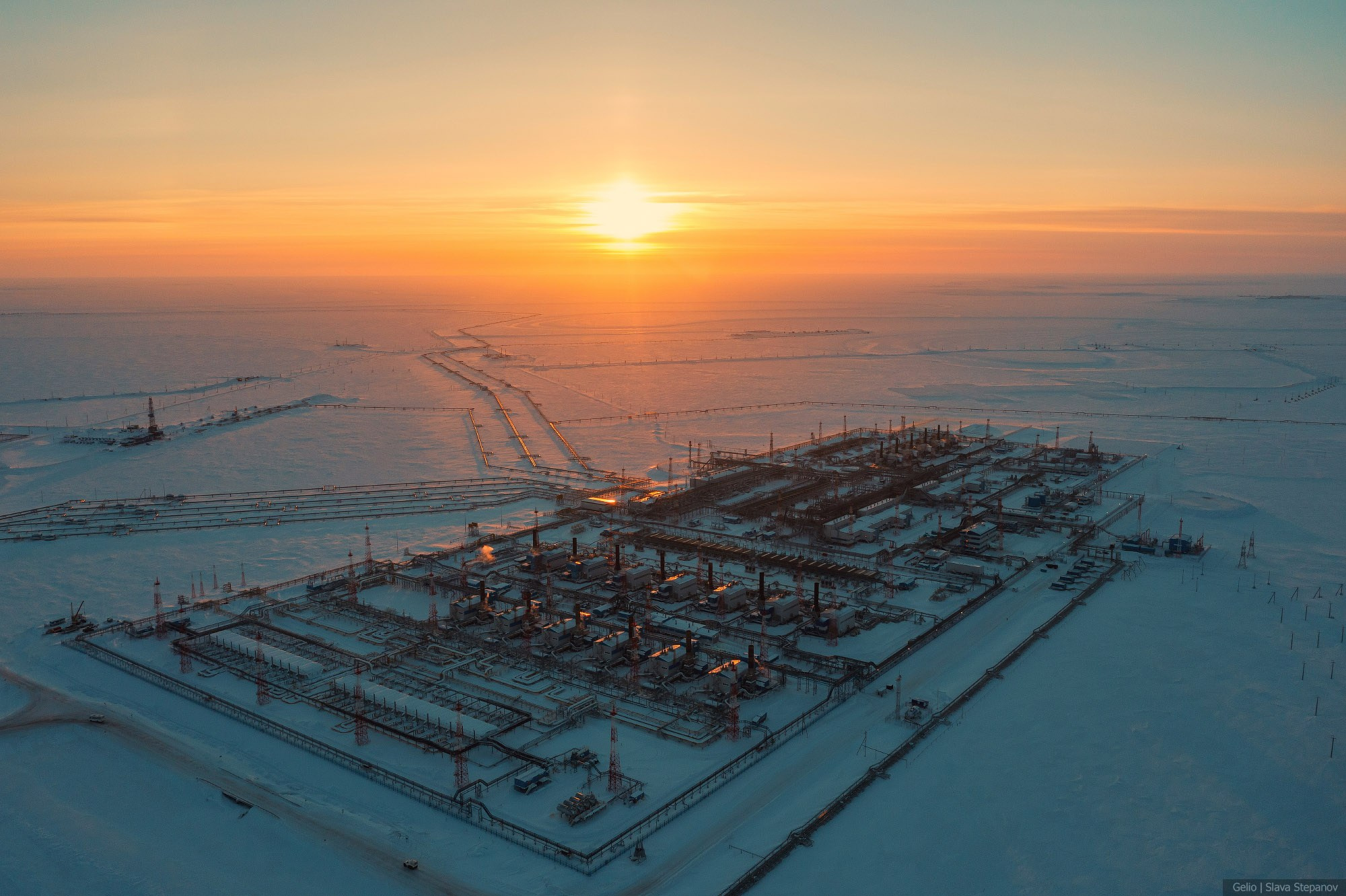 Огромный газодобывающий комплекс посреди заснеженной тундры, масштабная индустриальная панорама северного месторождения в лучах морозного солнца, фото Slava Stepanov.