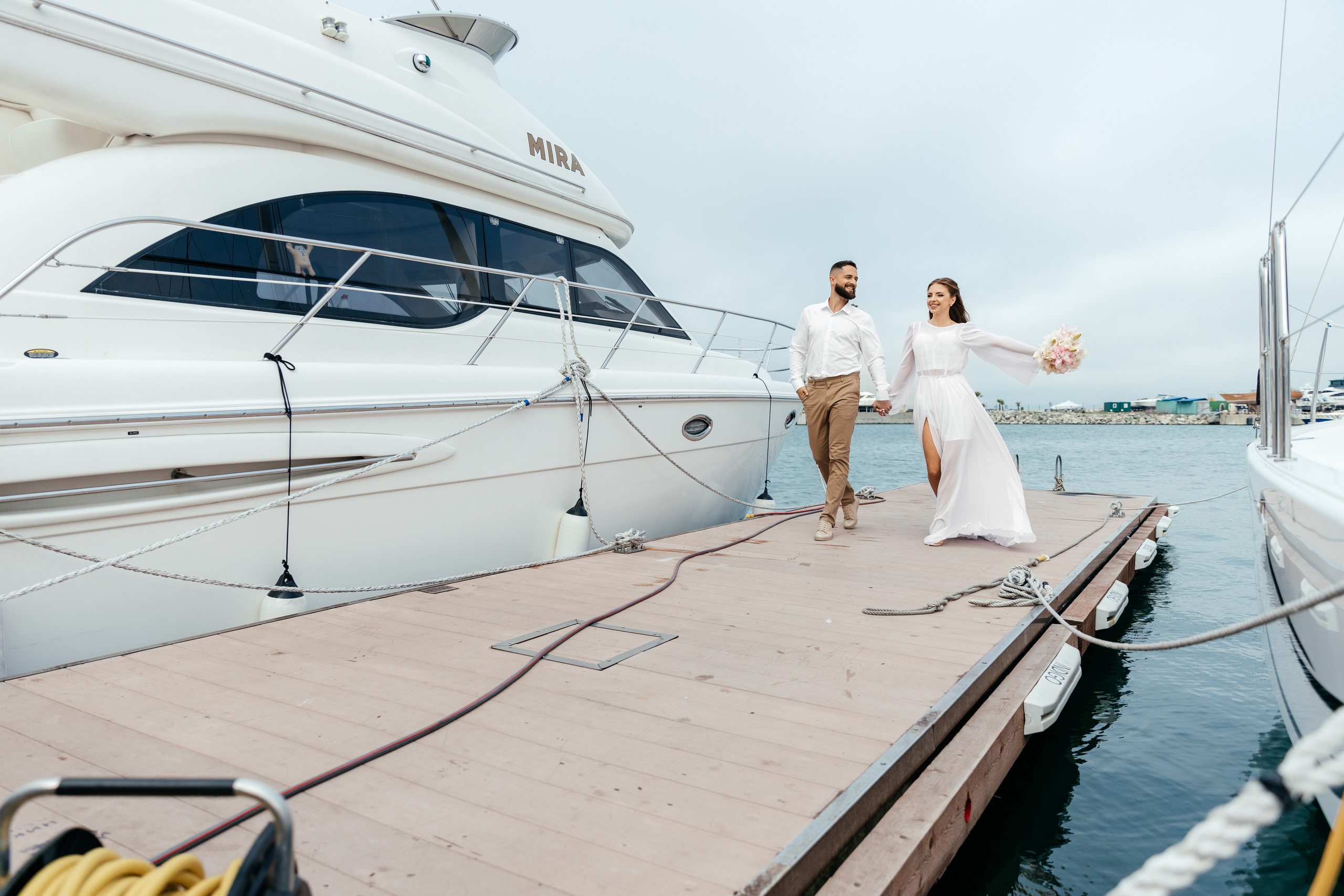 жених и невеста бегут по пирсу 