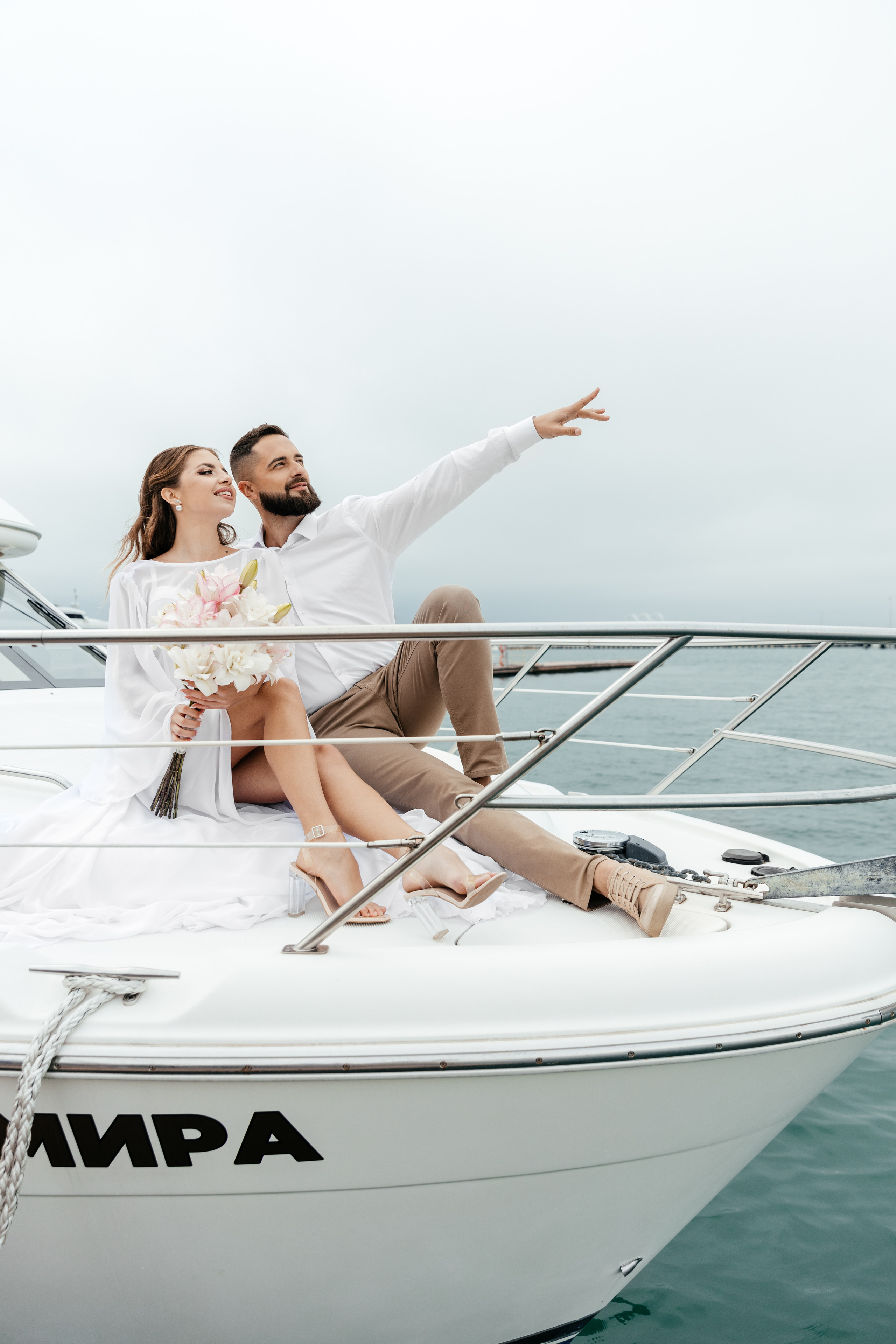 жених и невеста в белых нарядах на яхте 