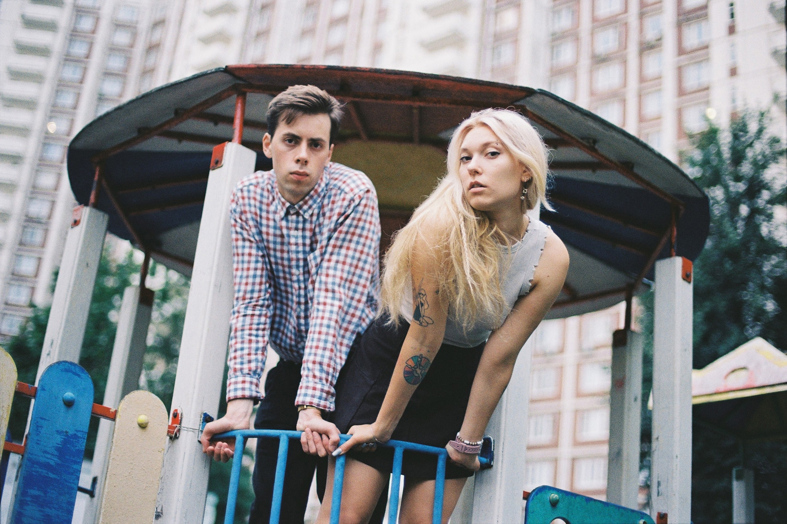 Парень с девушкой на детской площадке на фоне панельных многоэтажных домов