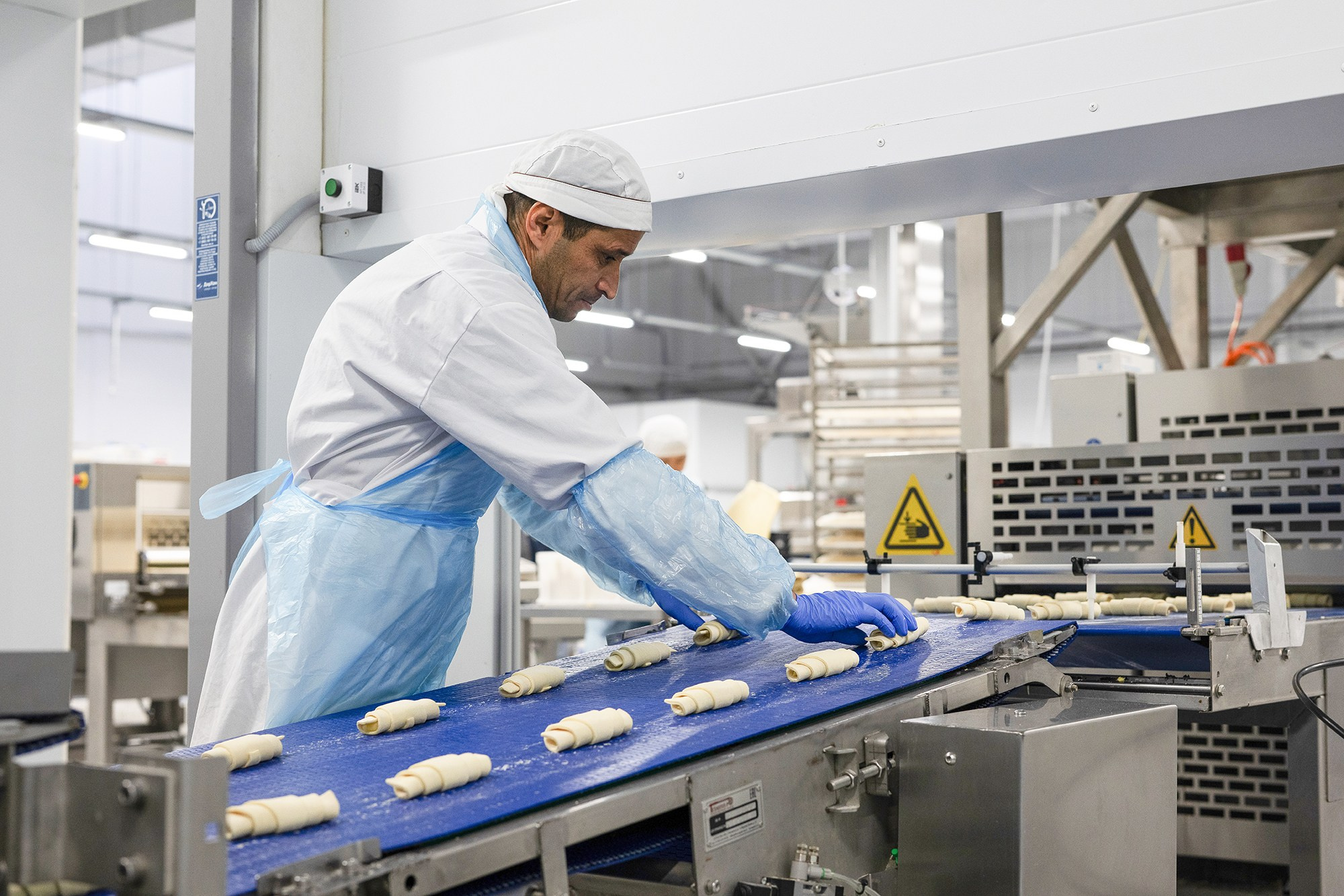 Мужчина на производственной линии сортирует выпечку