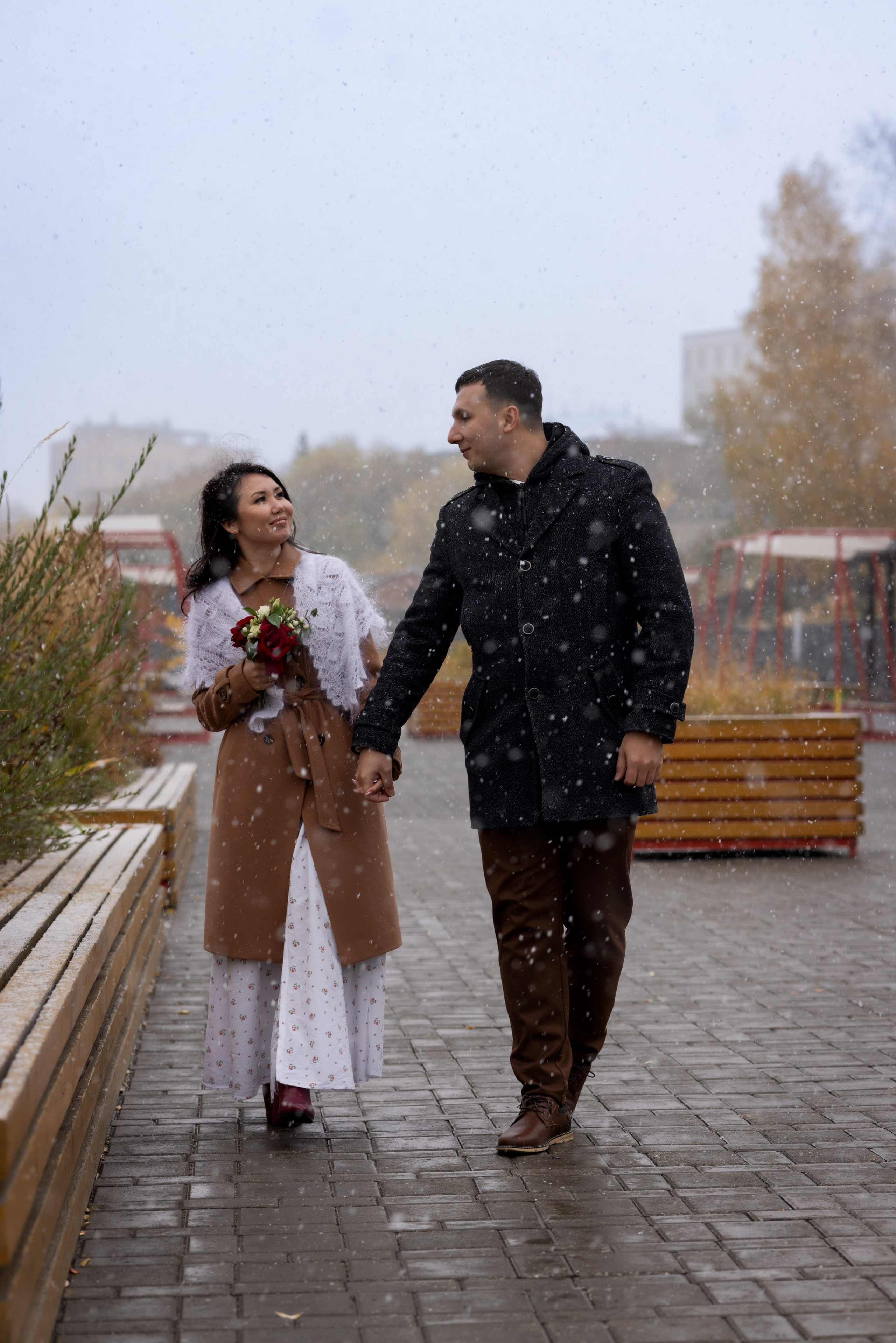 Зимняя, осенняя свадьба на улице: пара идет по городу