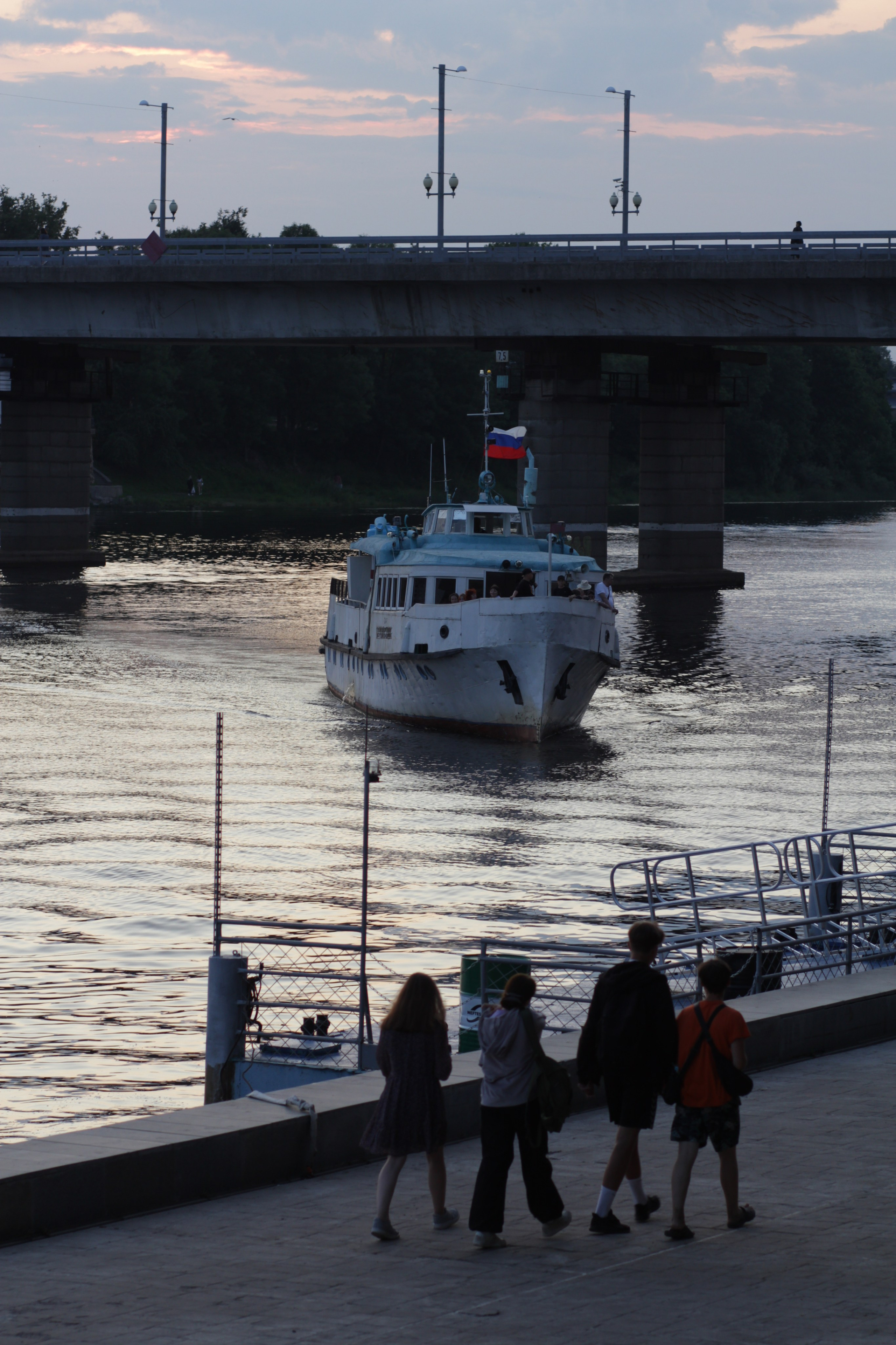 Прогулочное судно подходит к причалу у городской набережной