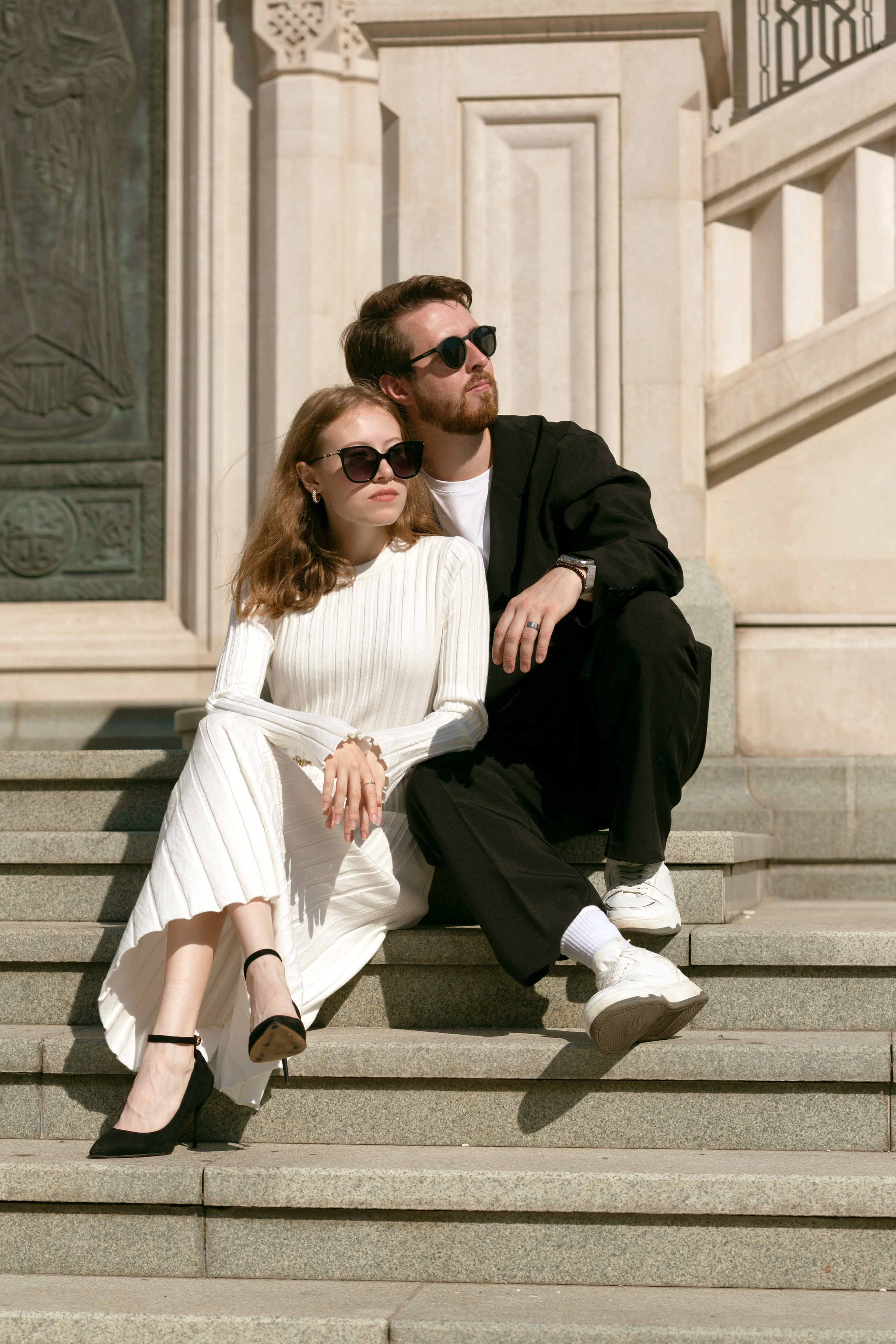Девушка сидит на ступеньках, мужчина рядом. Легкость и близость в кадре.