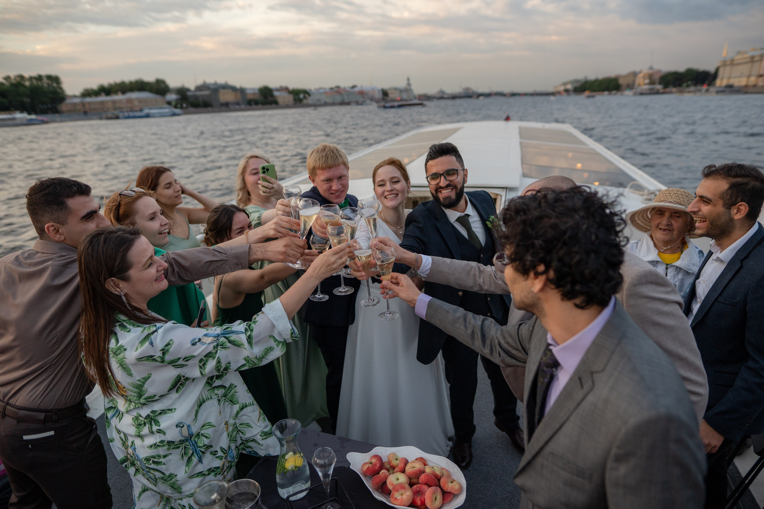 гости с женихом и невестой поднимают тост на яхте в акватории Невы