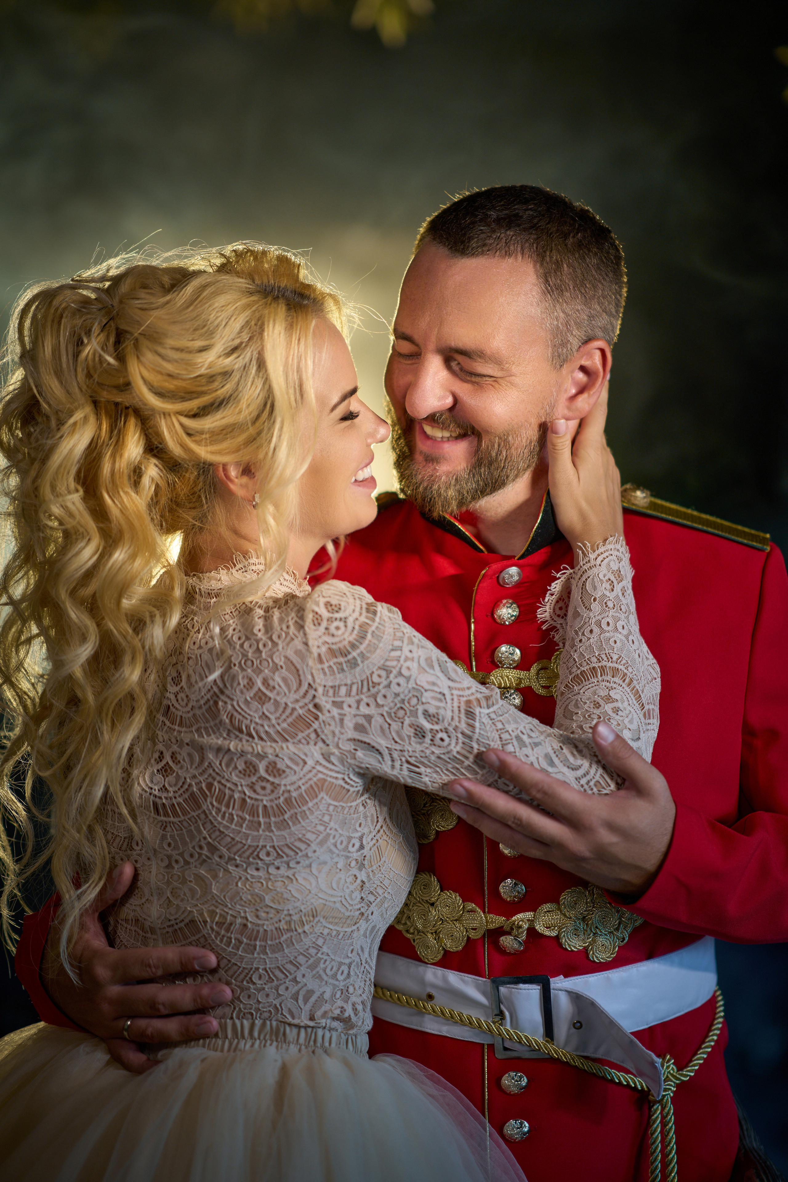 Пара в красном мундире и белом платье обнимается у каменных стен замка Гарибальди, отражая романтику и роскошь.