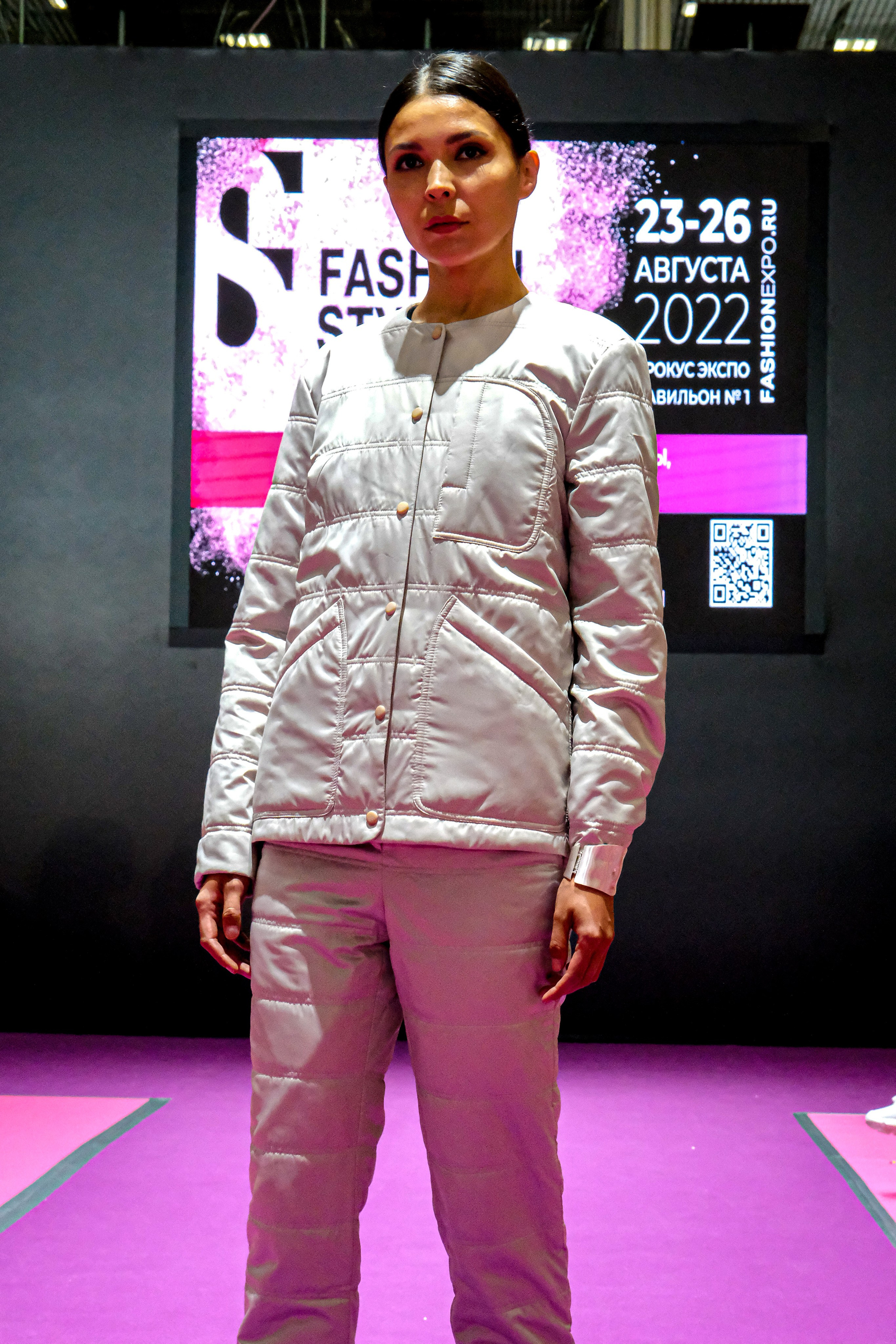  "Модели в ярких нарядах проходят по подиуму во время показа мод, освещенные яркими софитами и окруженные восторженными зрителями."