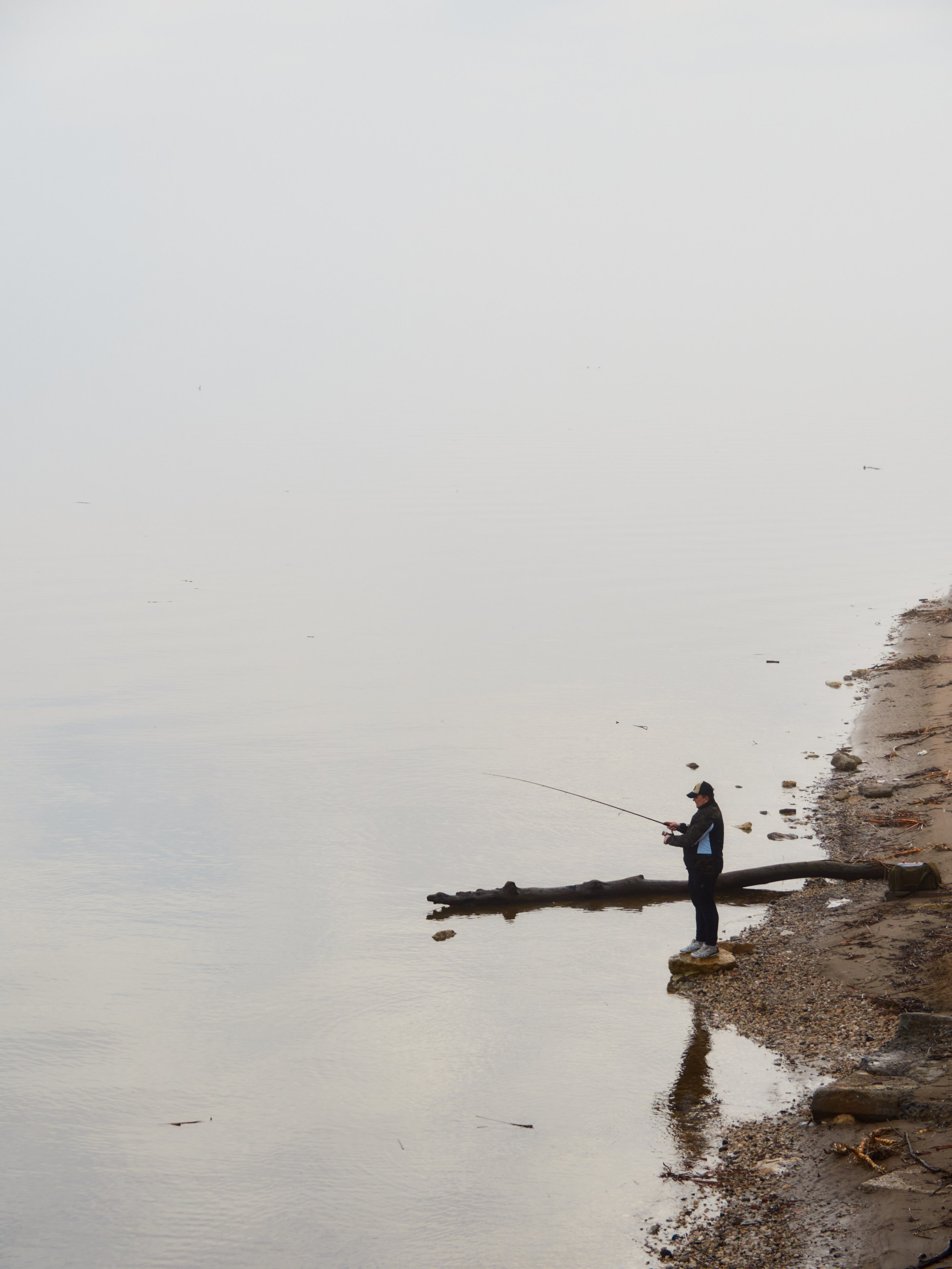Тихая река в туманное утро: вода зеркально отражает едва различимые силуэты деревьев