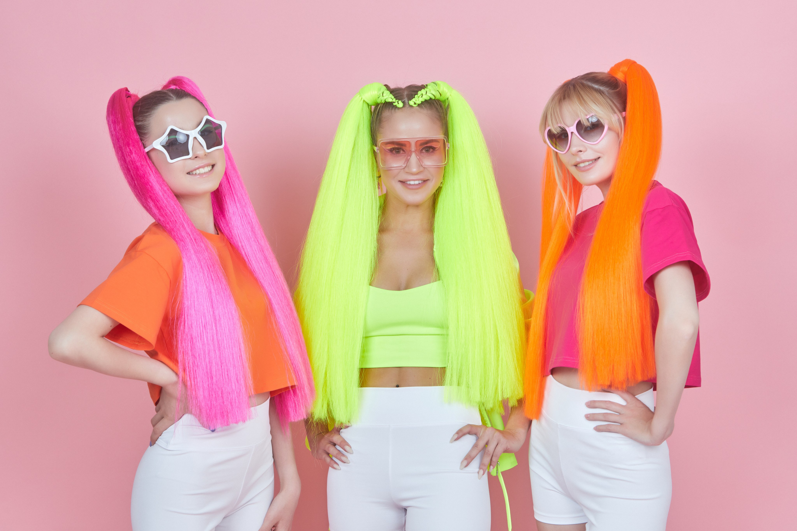Рекламная съёмка — три девушки с разноцветными хвостами на розовом фоне.