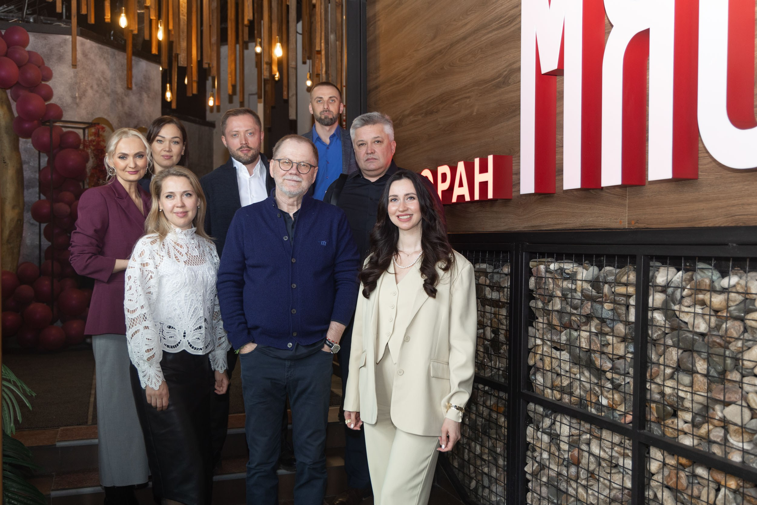 Группа людей в ресторане "Мясо" в Вологде позируют на общий снимок.