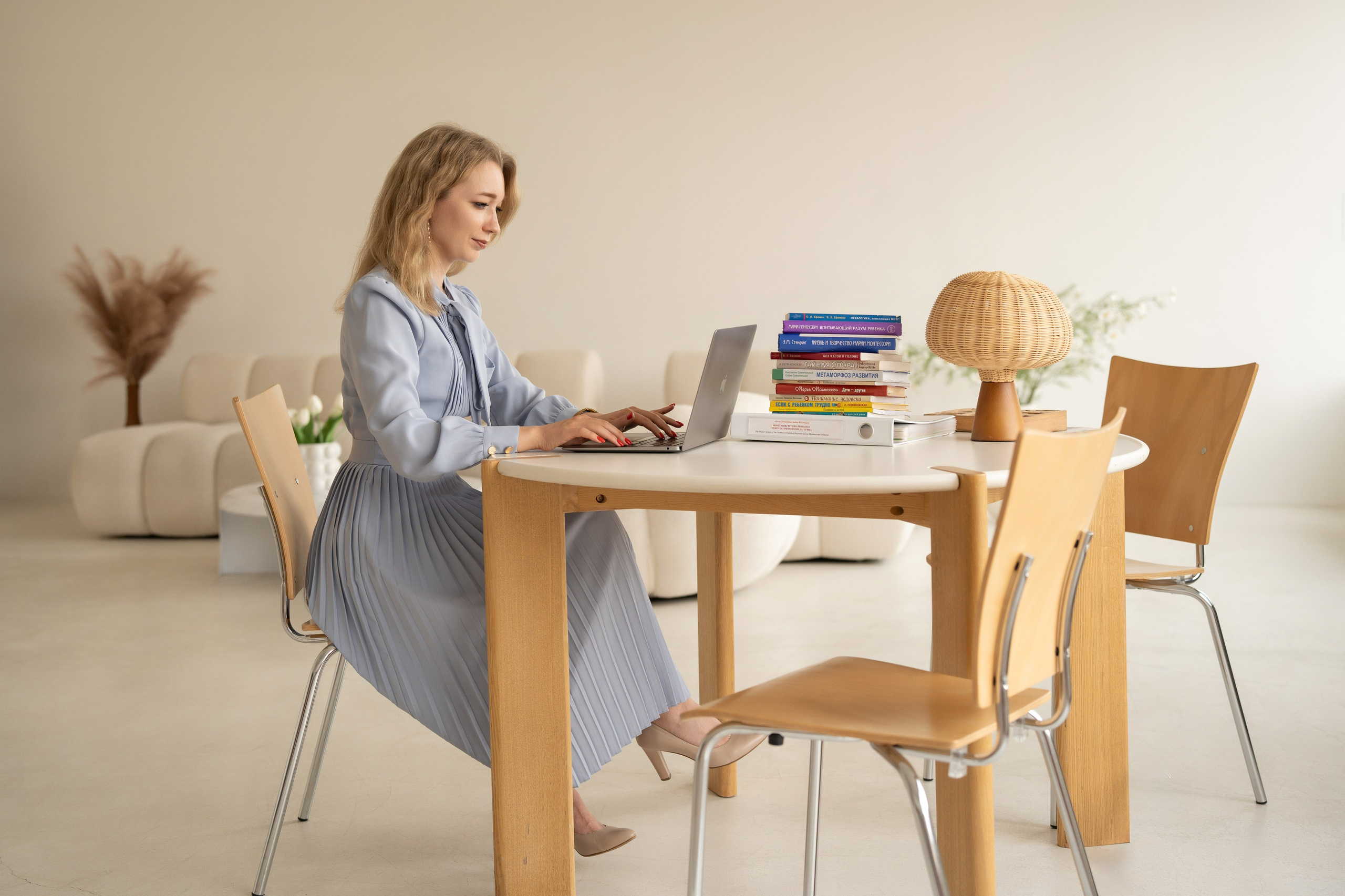 Бизнес-портрет женщины. Она сидит за столом и работает на ноутбуком.