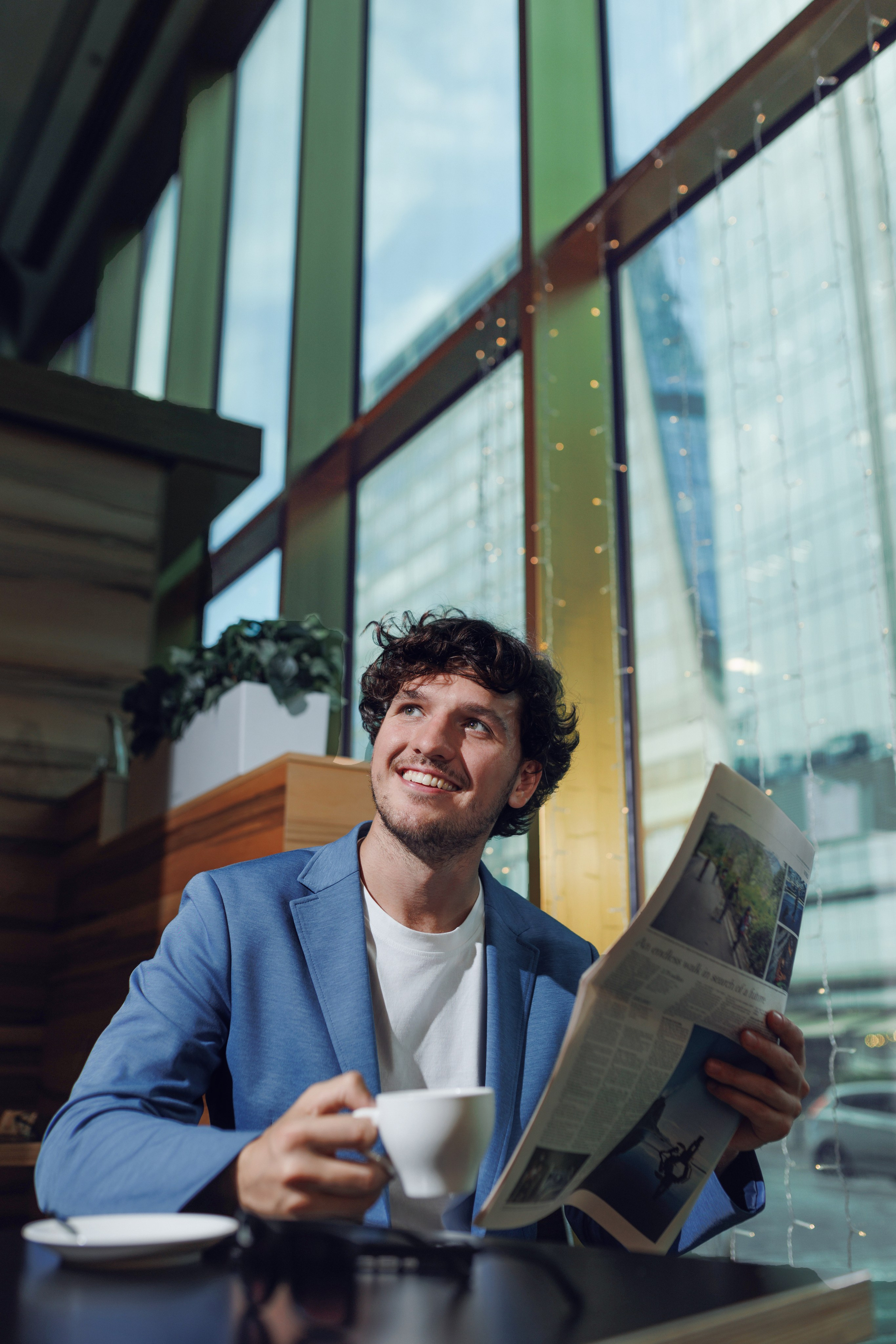 Мужчина сидит в кафе, на заднем плане виден деловой центр Москва-Сити.